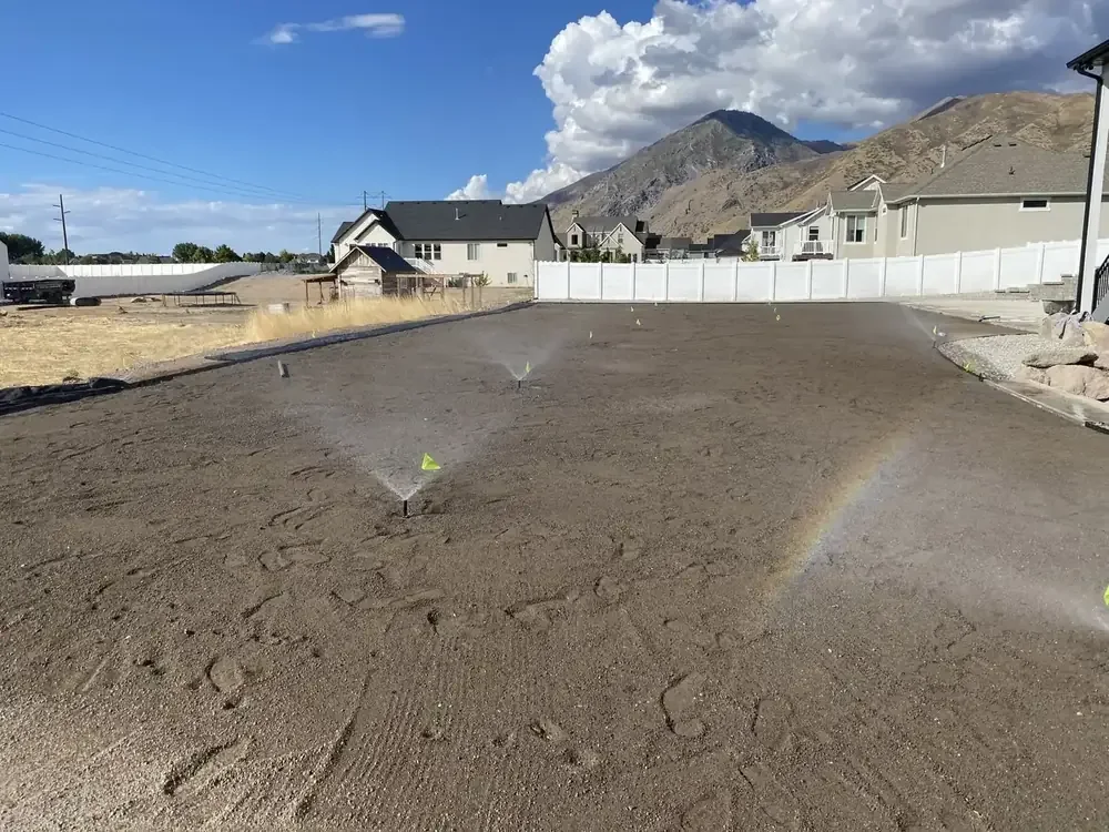 Sprinklers watering a newly graded Utah yard with a rainbow