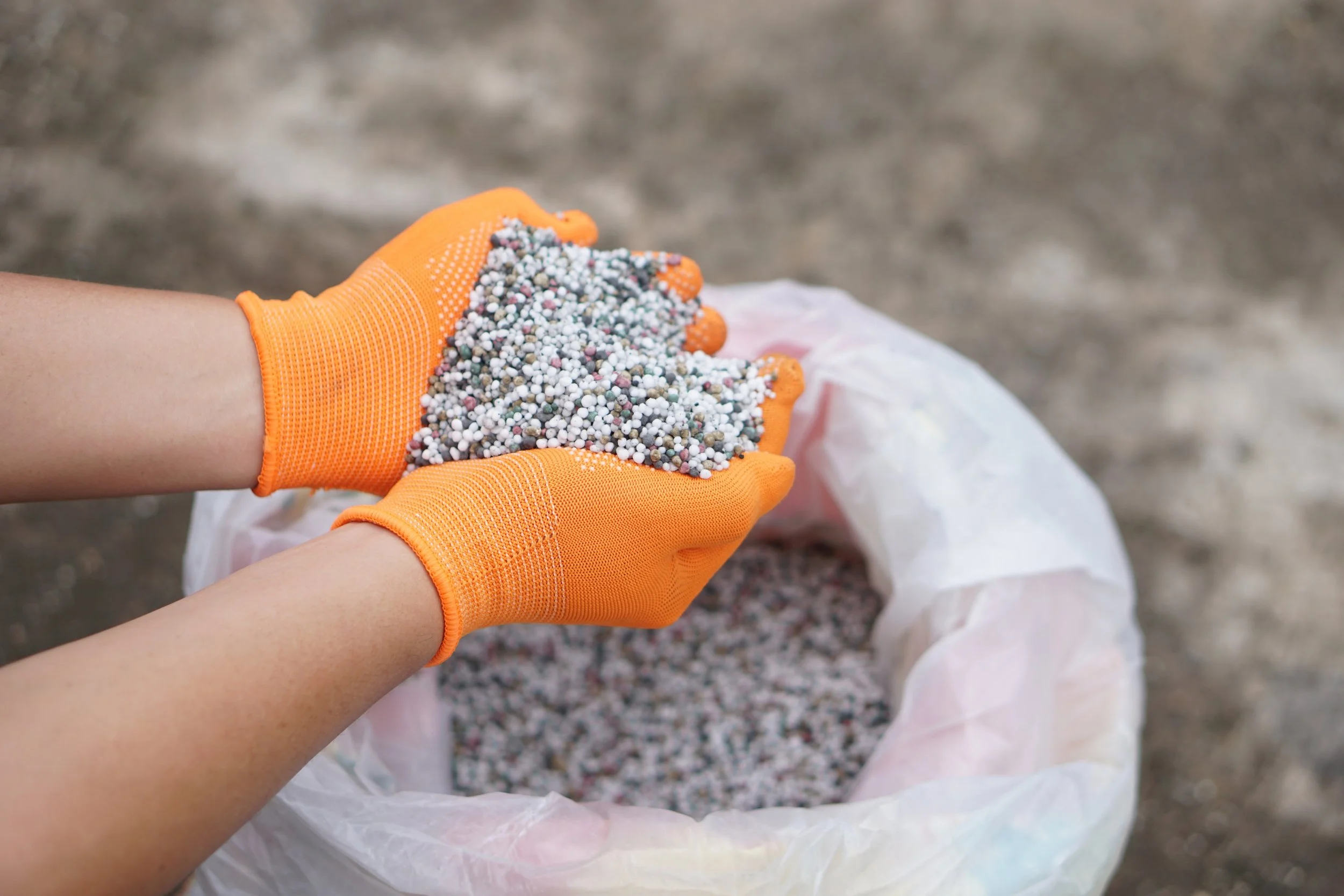 Hands in orange gloves holding Fertilizer in Bluffdale Utah