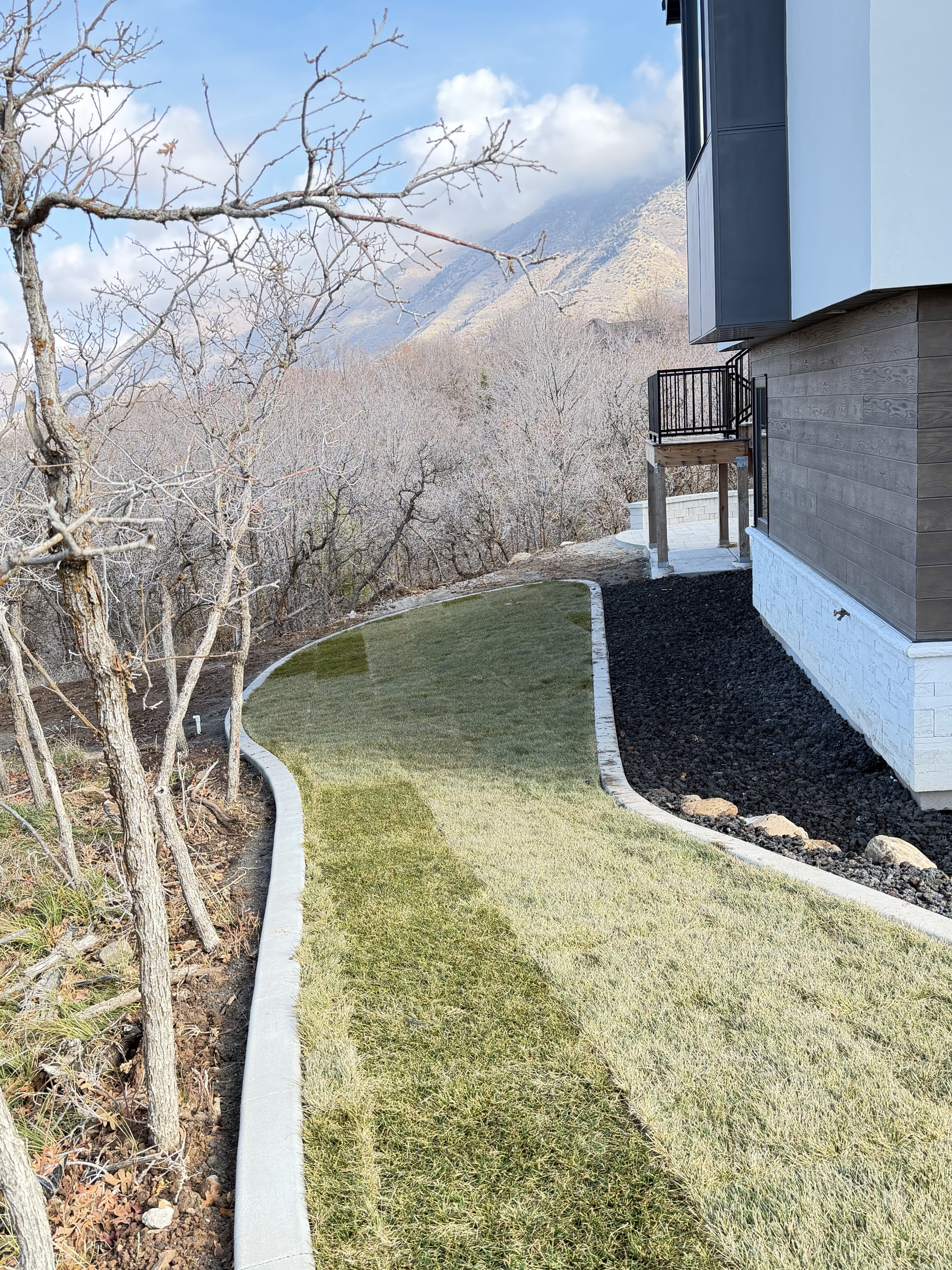 Lush grass and efficient sprinkler system in Herriman Utah backyard after landscaping installation