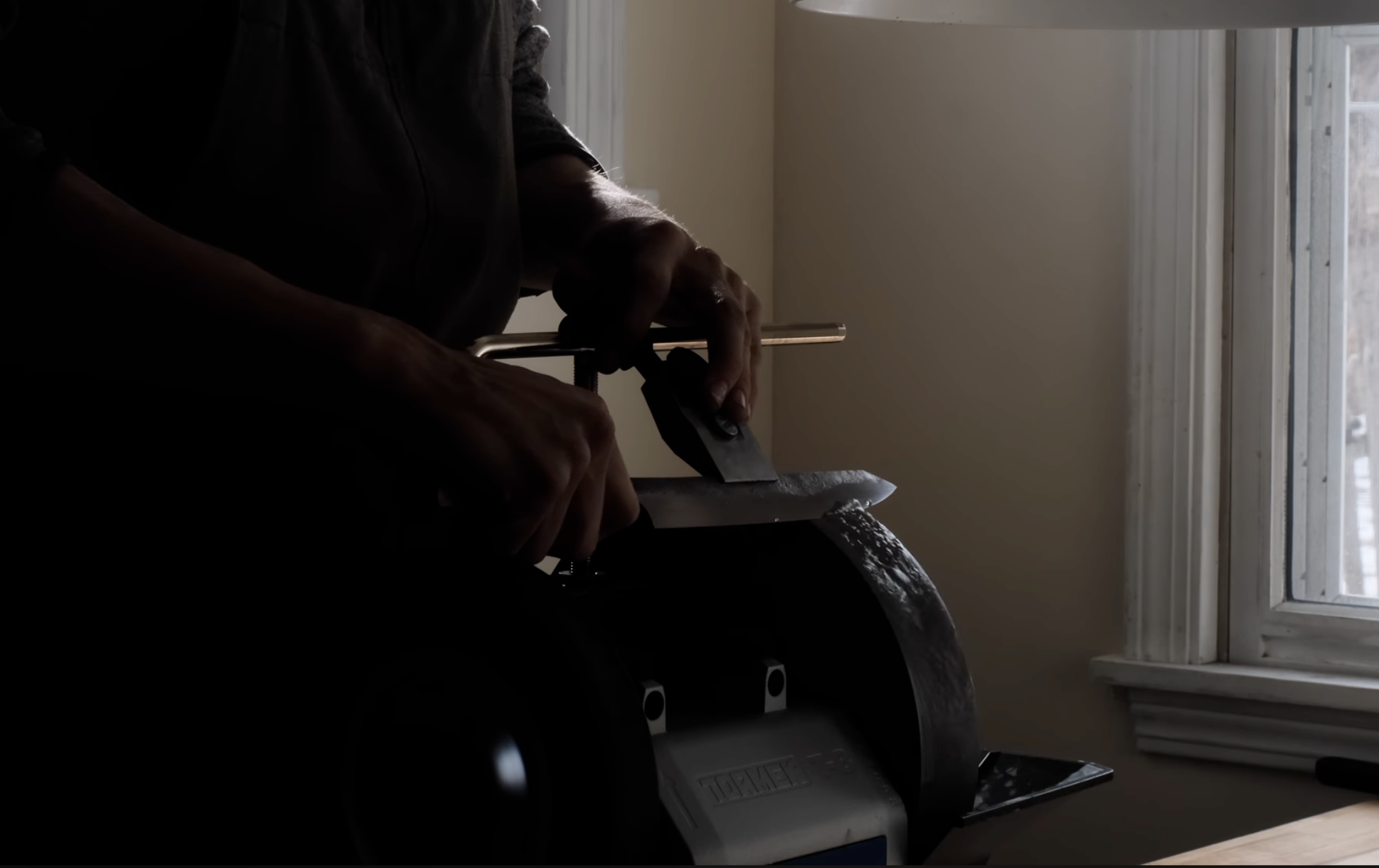 A person using a tormek to sharpen a knife.