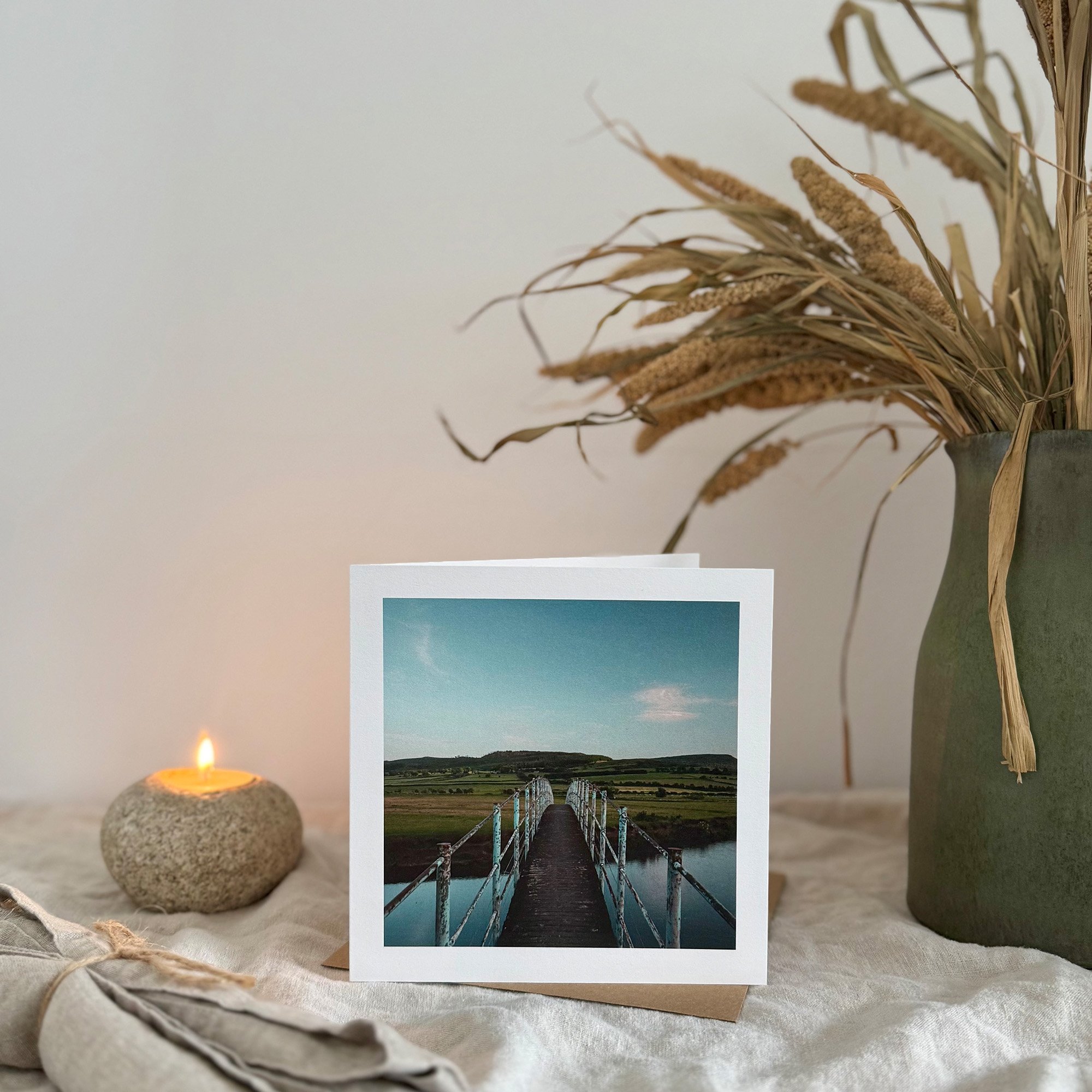 Suspension into Landscape greeting card styled with a stone candle and natural décor on a soft linen surface.