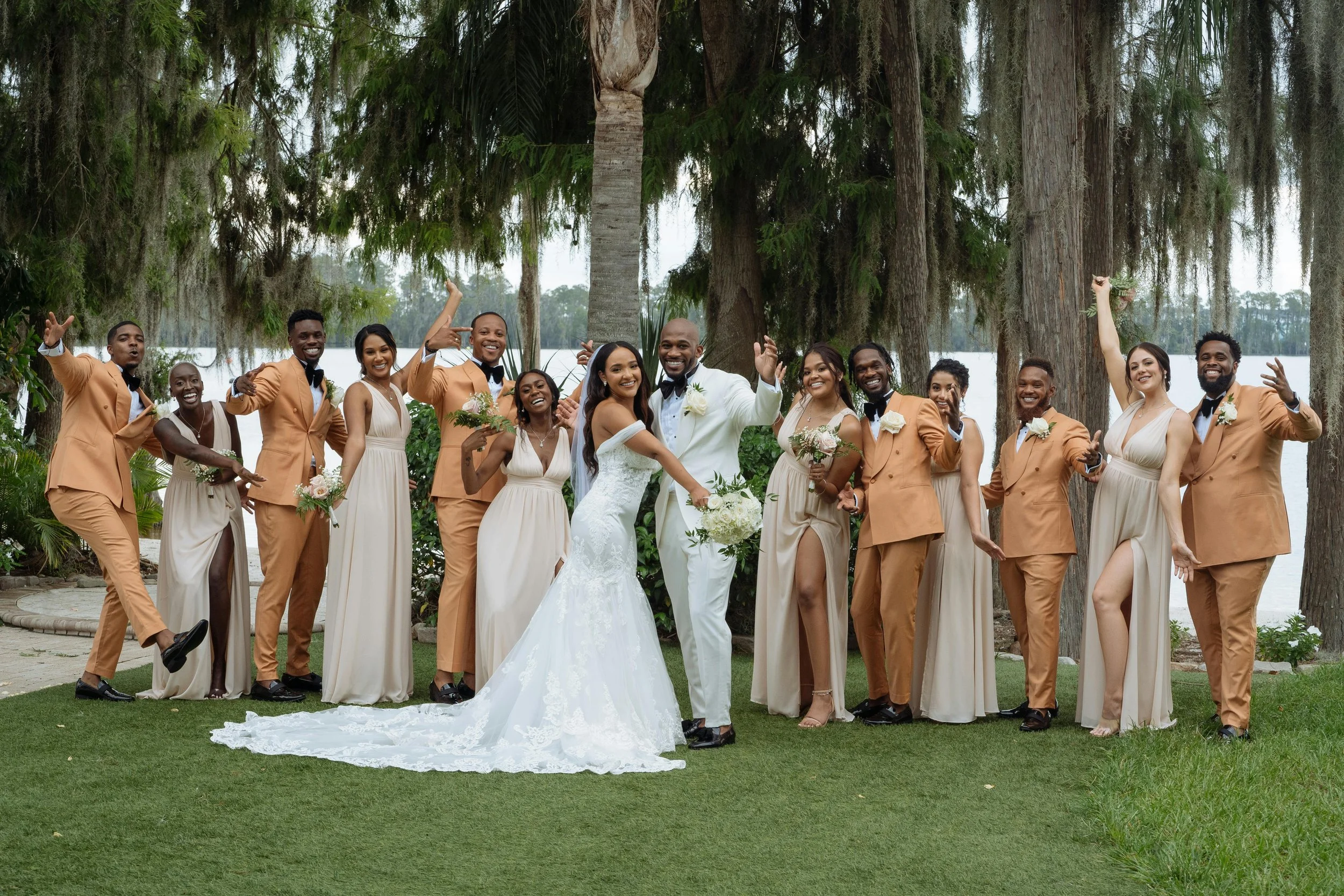 Bride and groom posing with their family on their wedding day. Everyone is in alternating shades of dusty pink and muted terracotta.