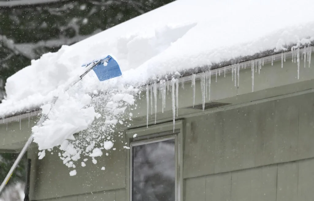 roof raking on snowy roof with icicles