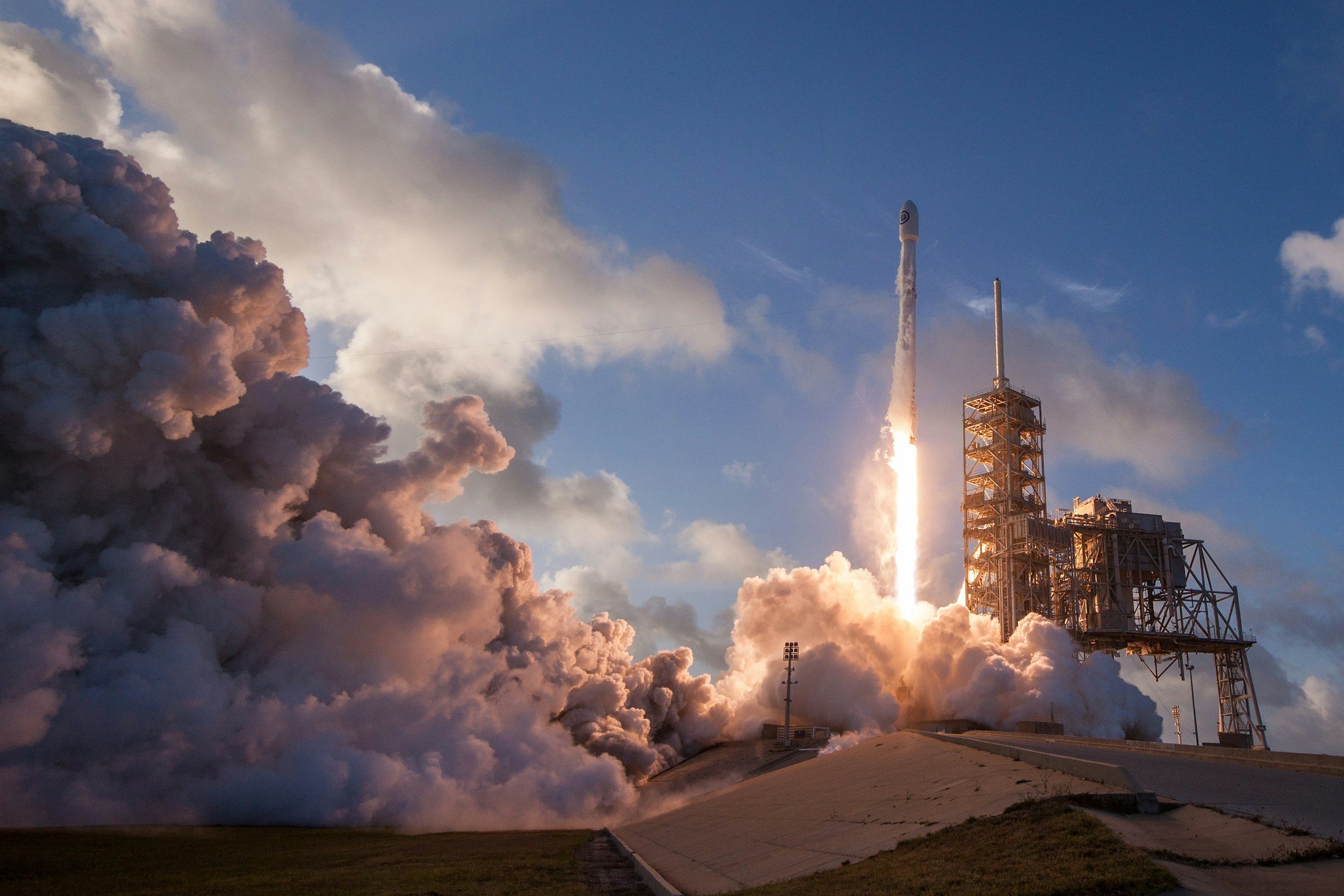 Rocket launching with smoke and flames, blue sky background.