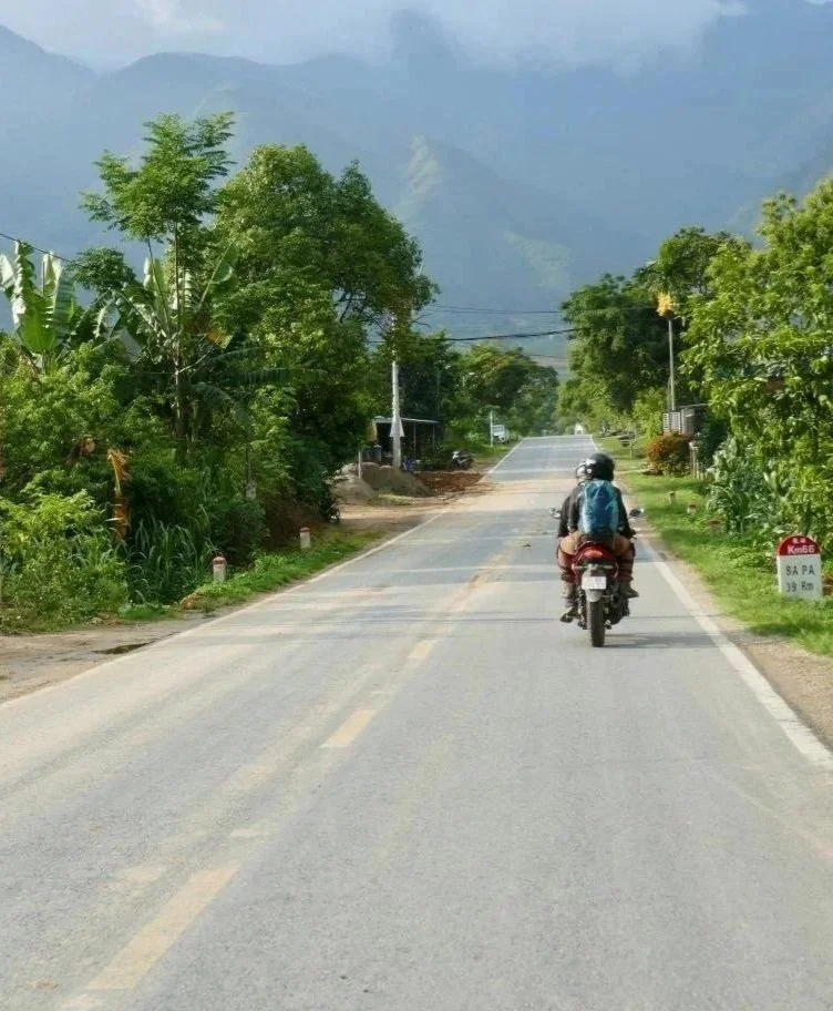 Adult in midlife adventuring down exotic road on motorbike