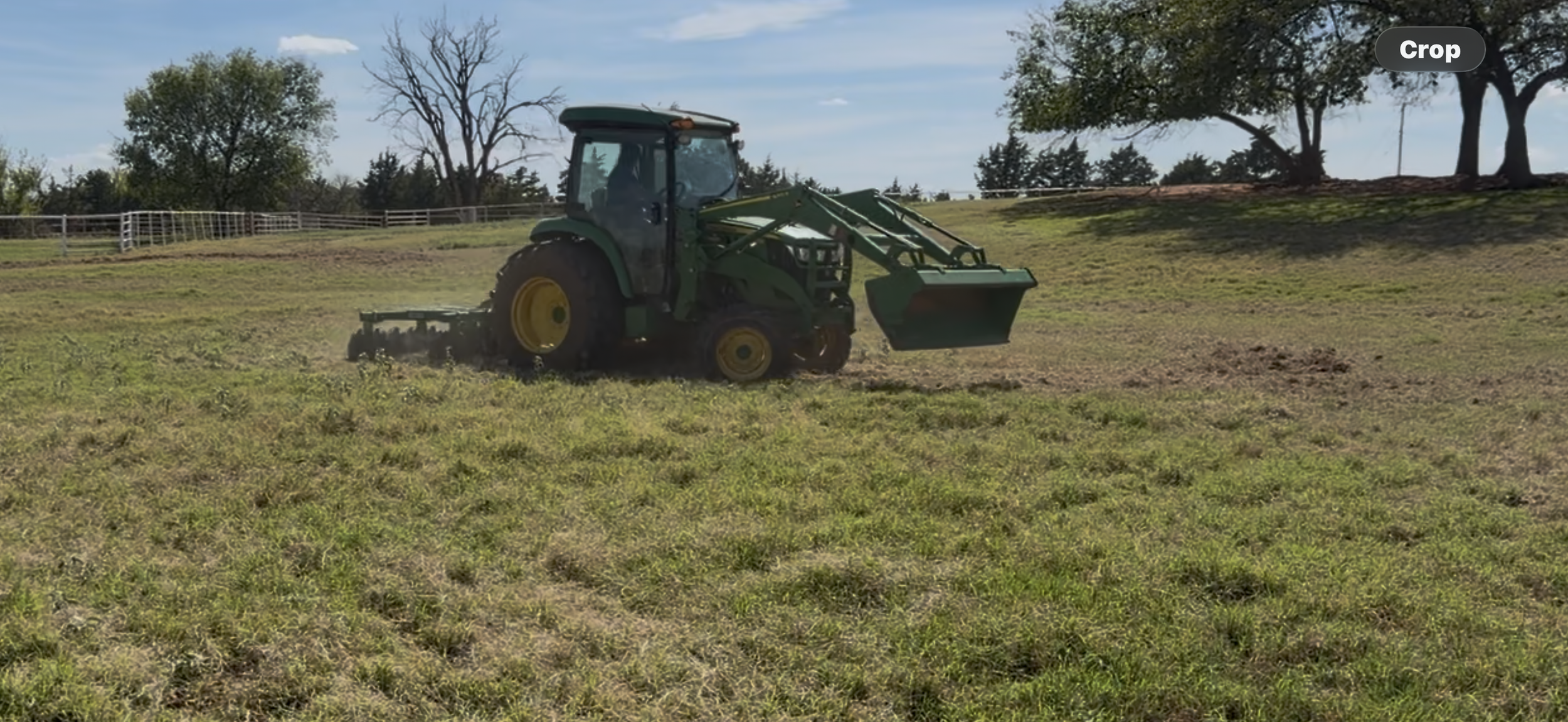 John Deere tractor preparing a grassy field at Rein Maker Ranch Farmstead in Oklahoma for five raised strawberry beds to be planted in October.