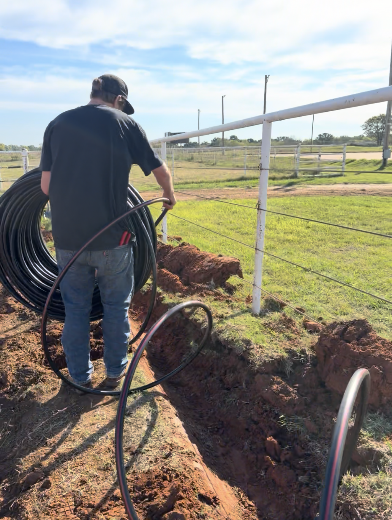 man with irrigation tubing unrolling it into a trench