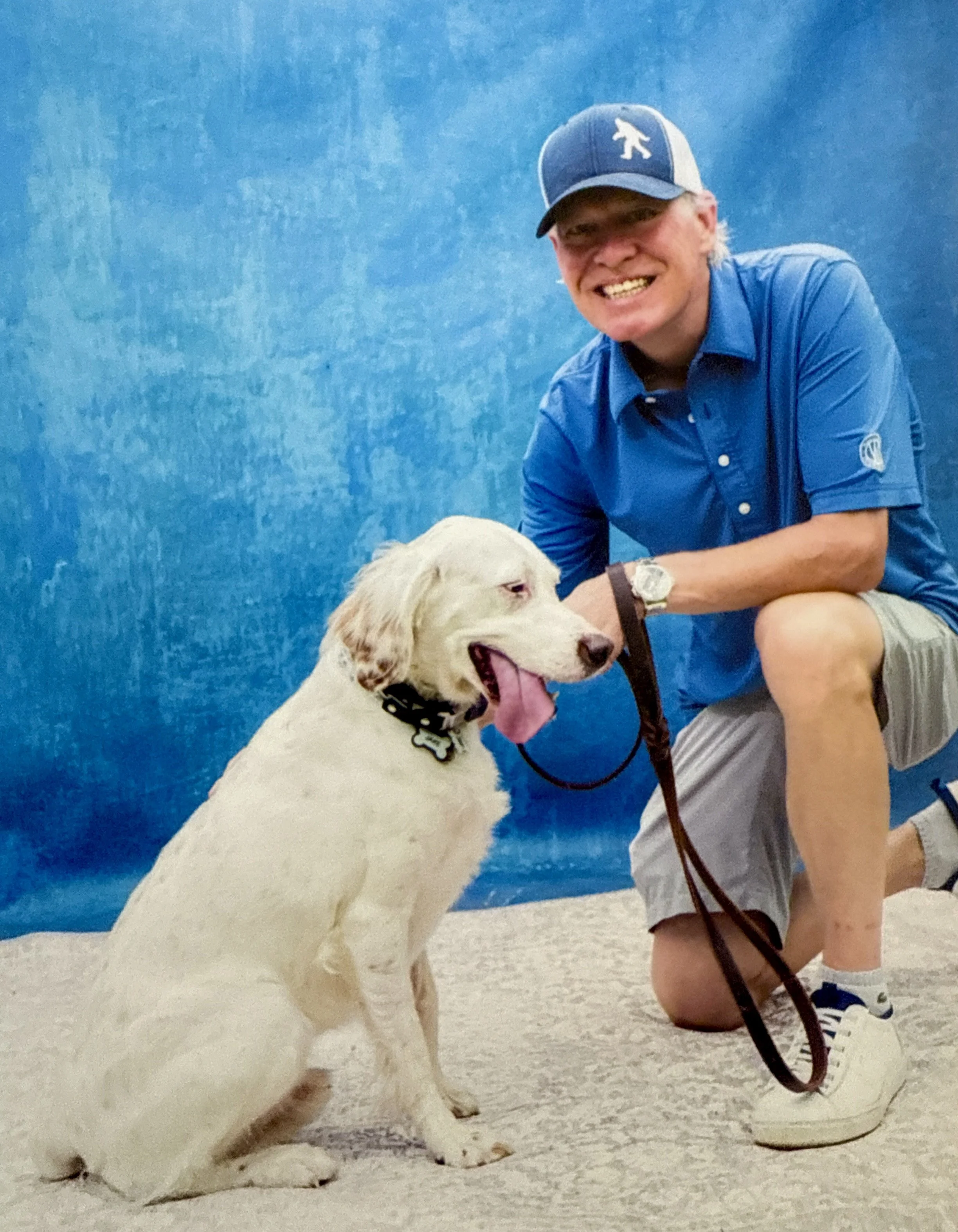 Man wearing glasses and a blue suit, smiling outdoors