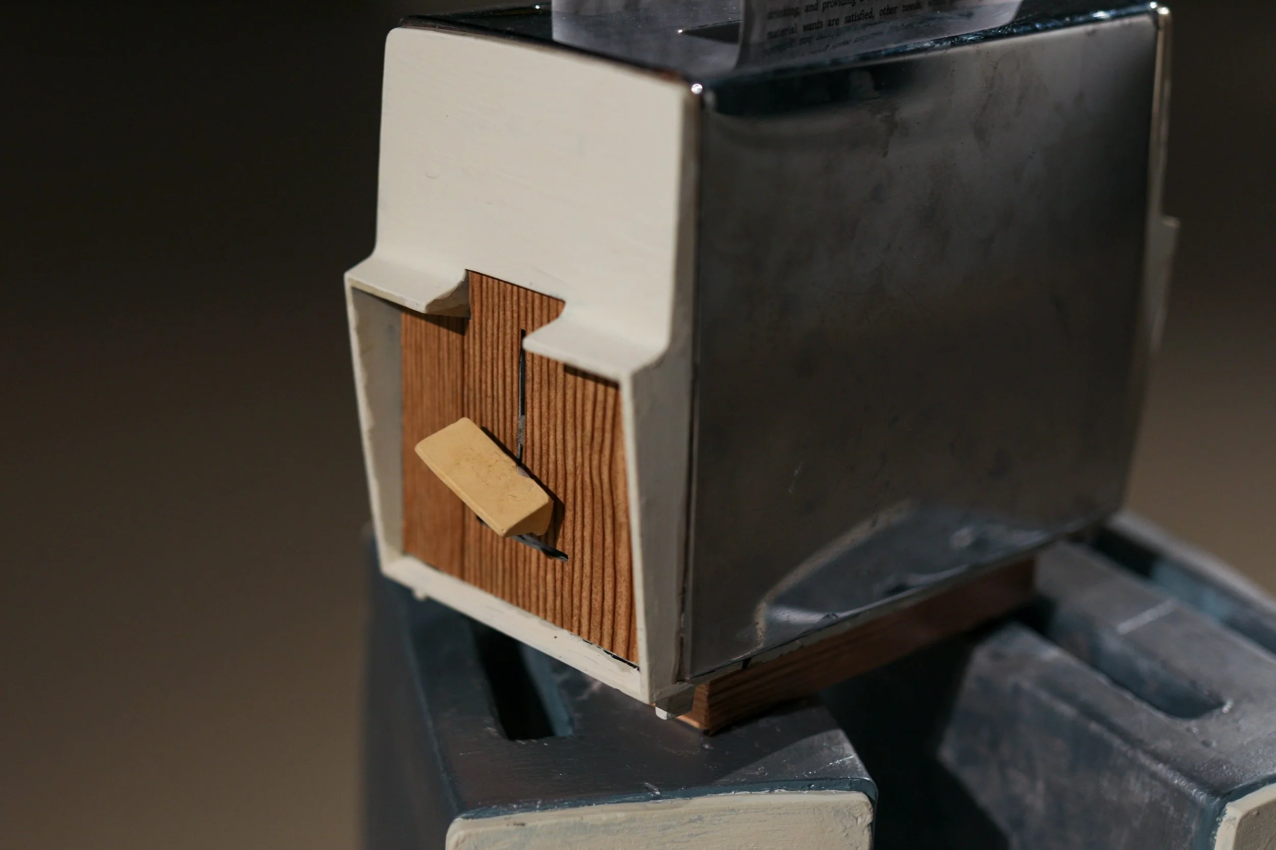 Detail: Becky Sellinger, La Conquête du pain, 2026, plaster, paint, mid century toaster, paper, faux wood drawer liner,  motor 

photo credit: Theo Cote