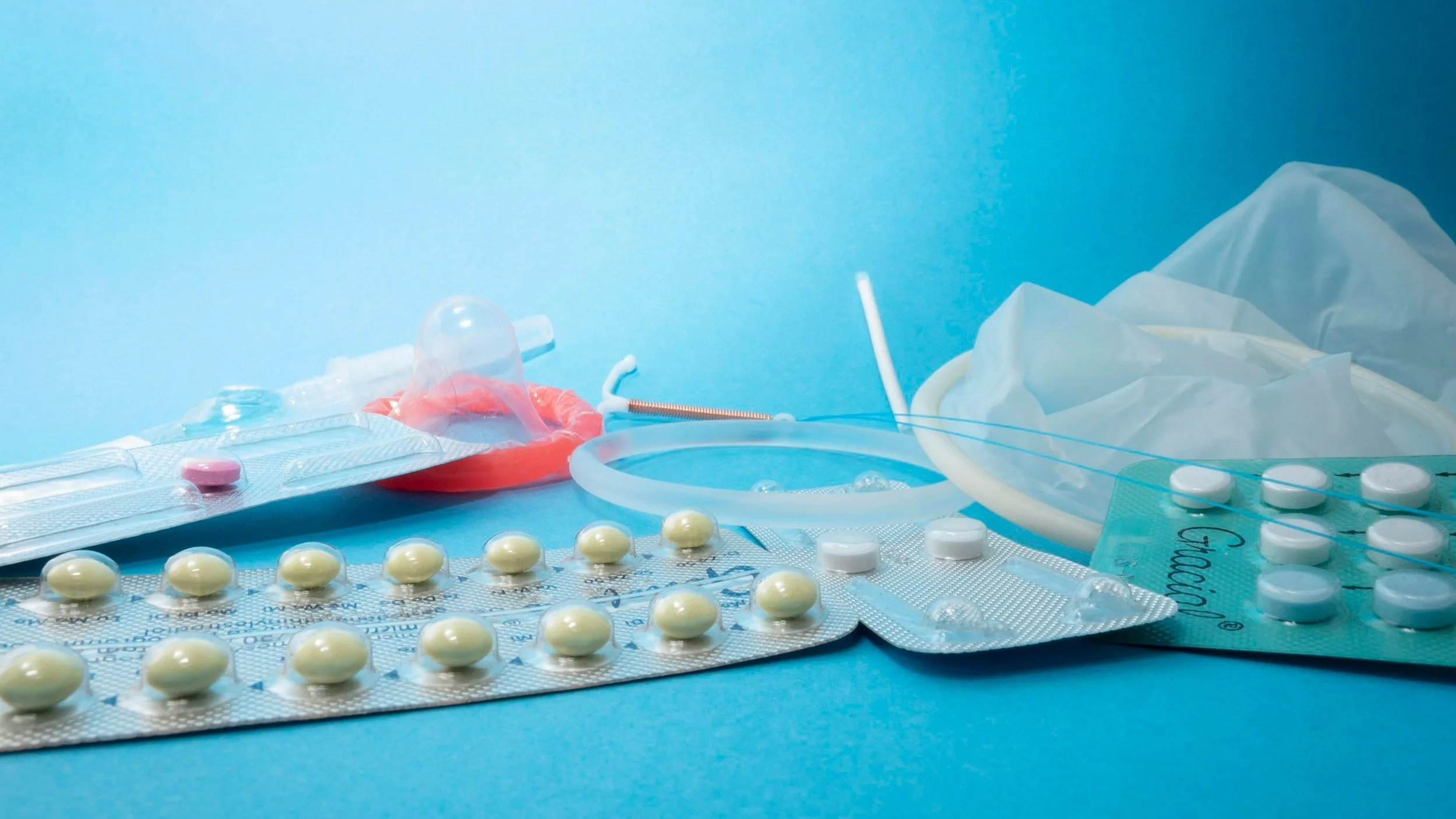 Various birth control methods including pills and condoms on a blue background