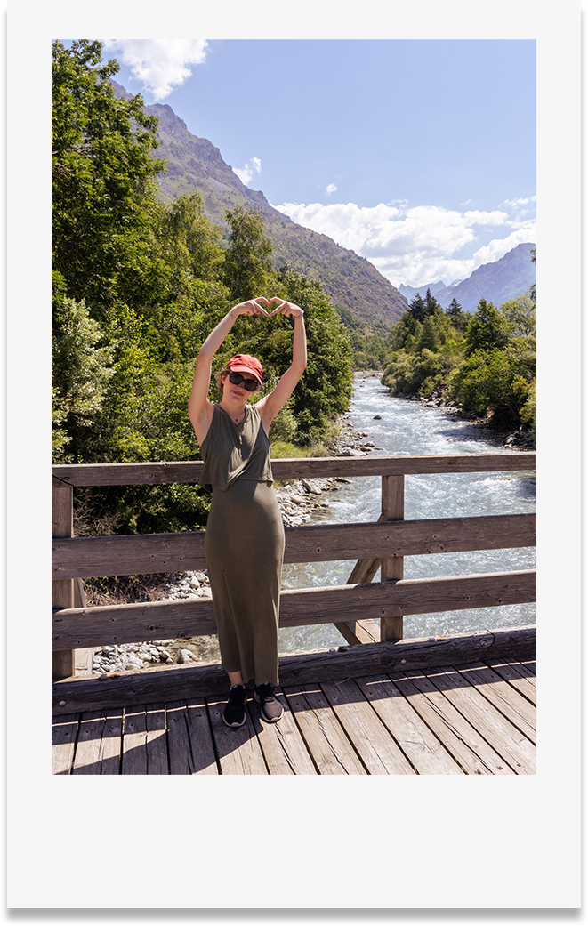 Photo style polaroid photographe qui fait un coeur avec ses mains devant paysages de montagnes