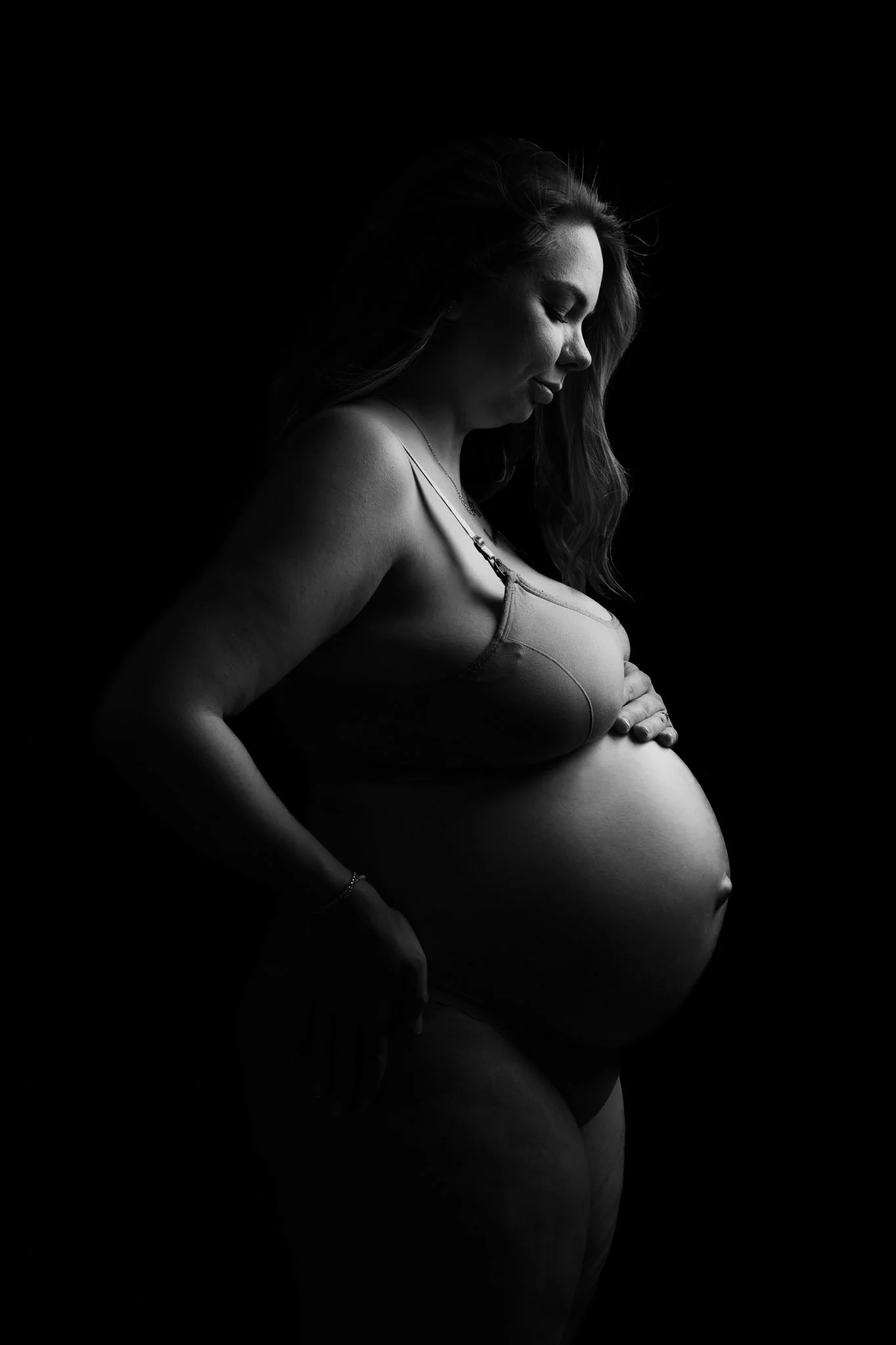 Photo en N&B femme enceinte qui regarde son ventre effet clair obscur