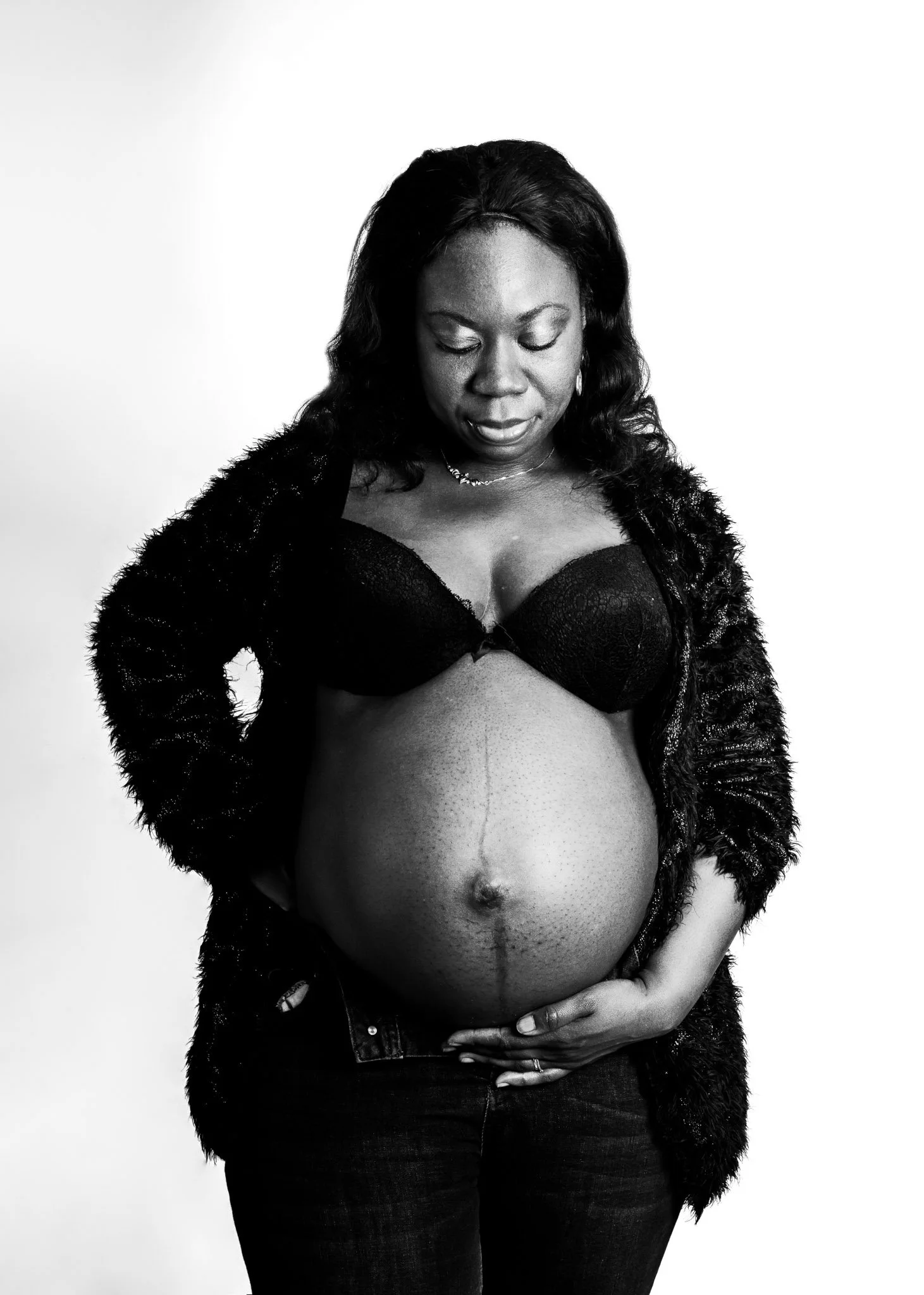 Photo en N&B femme enceinte gilet et jean , qui regarde son ventre