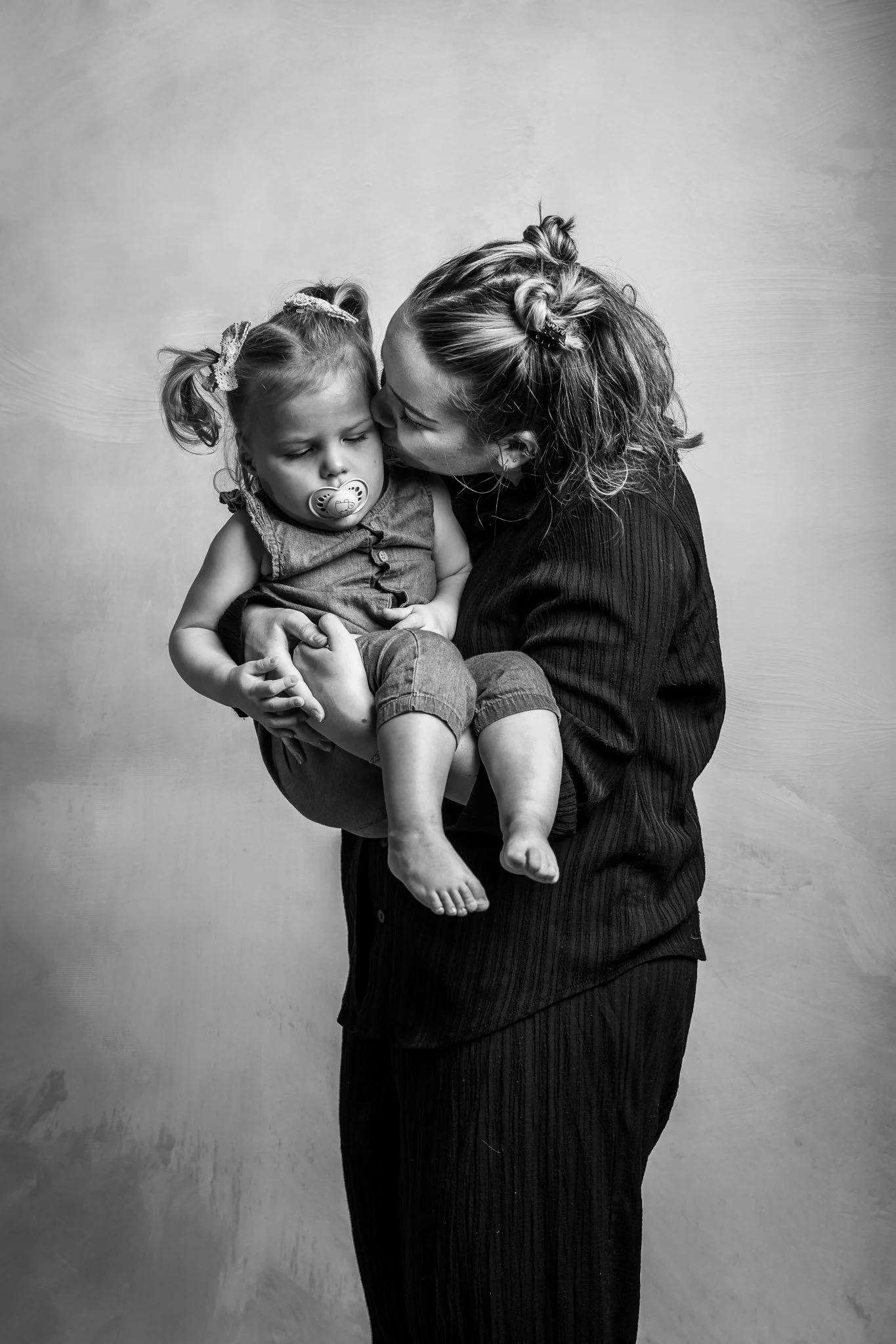 Photo de famille en N&B tante qui tient sa nièce de 2 ans et bisou sur sa joue