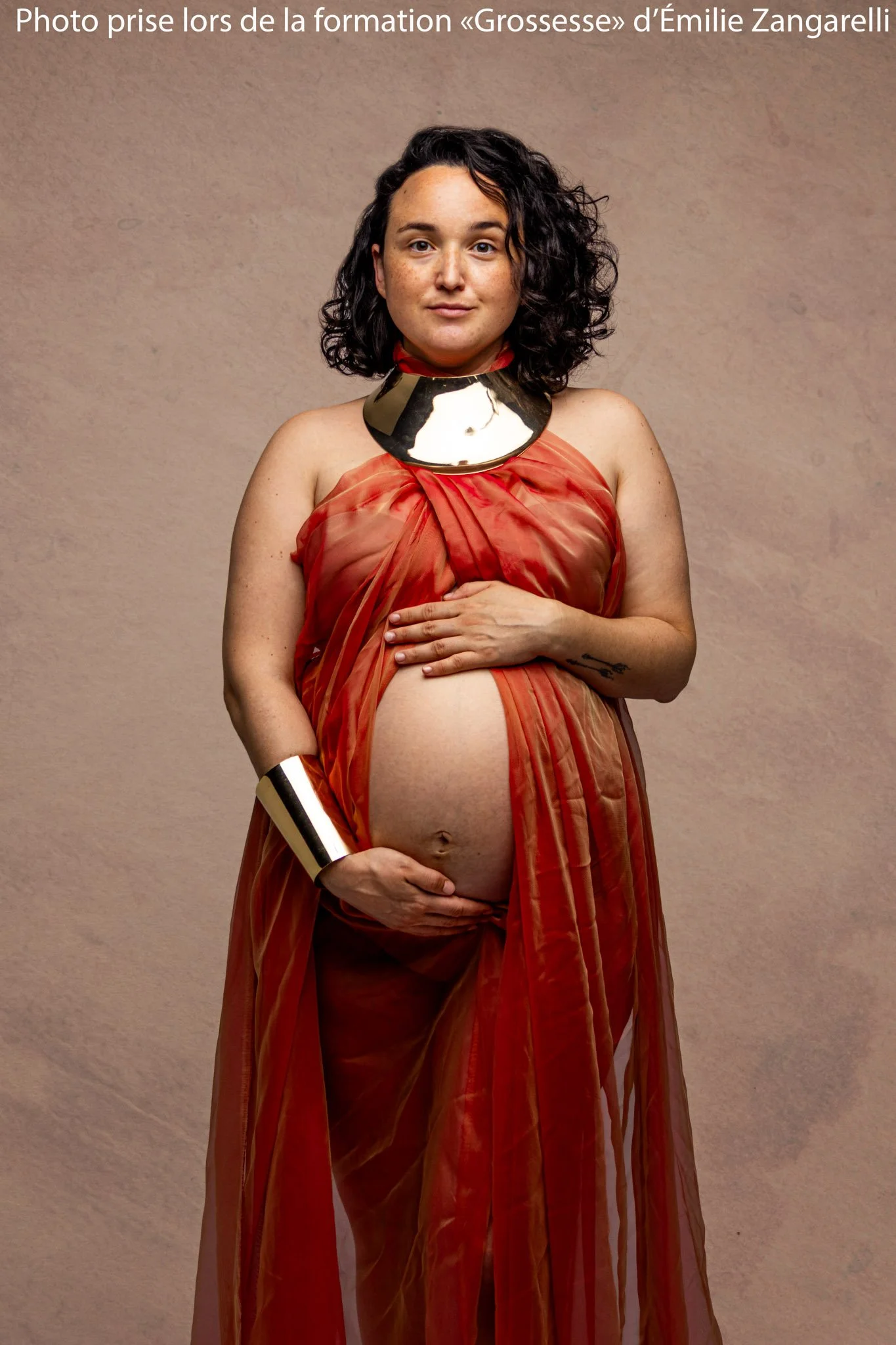 Femme enceinte robe orangée et collier doré