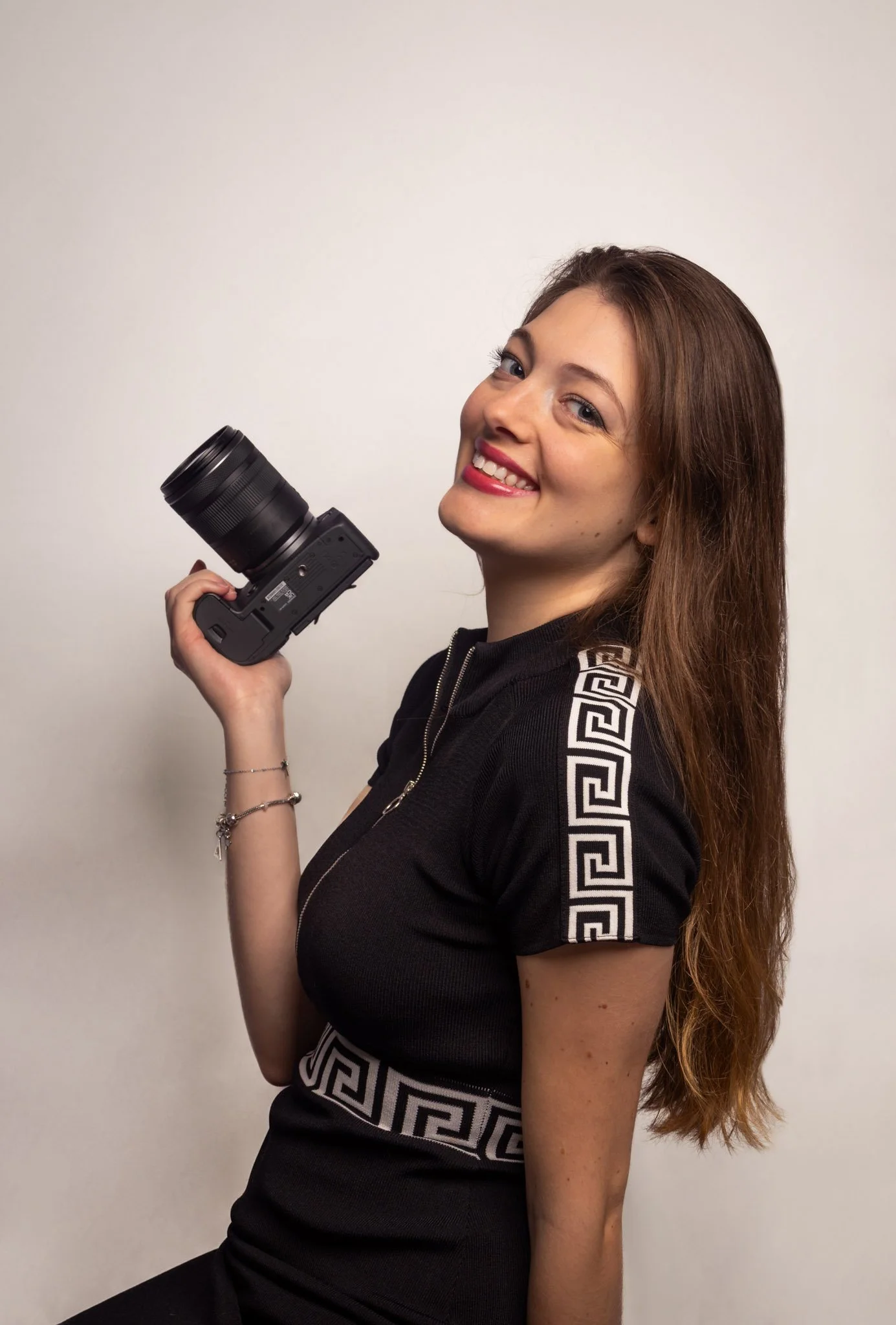 Photographe en robe noire qui sourit et tient son appareil à la main