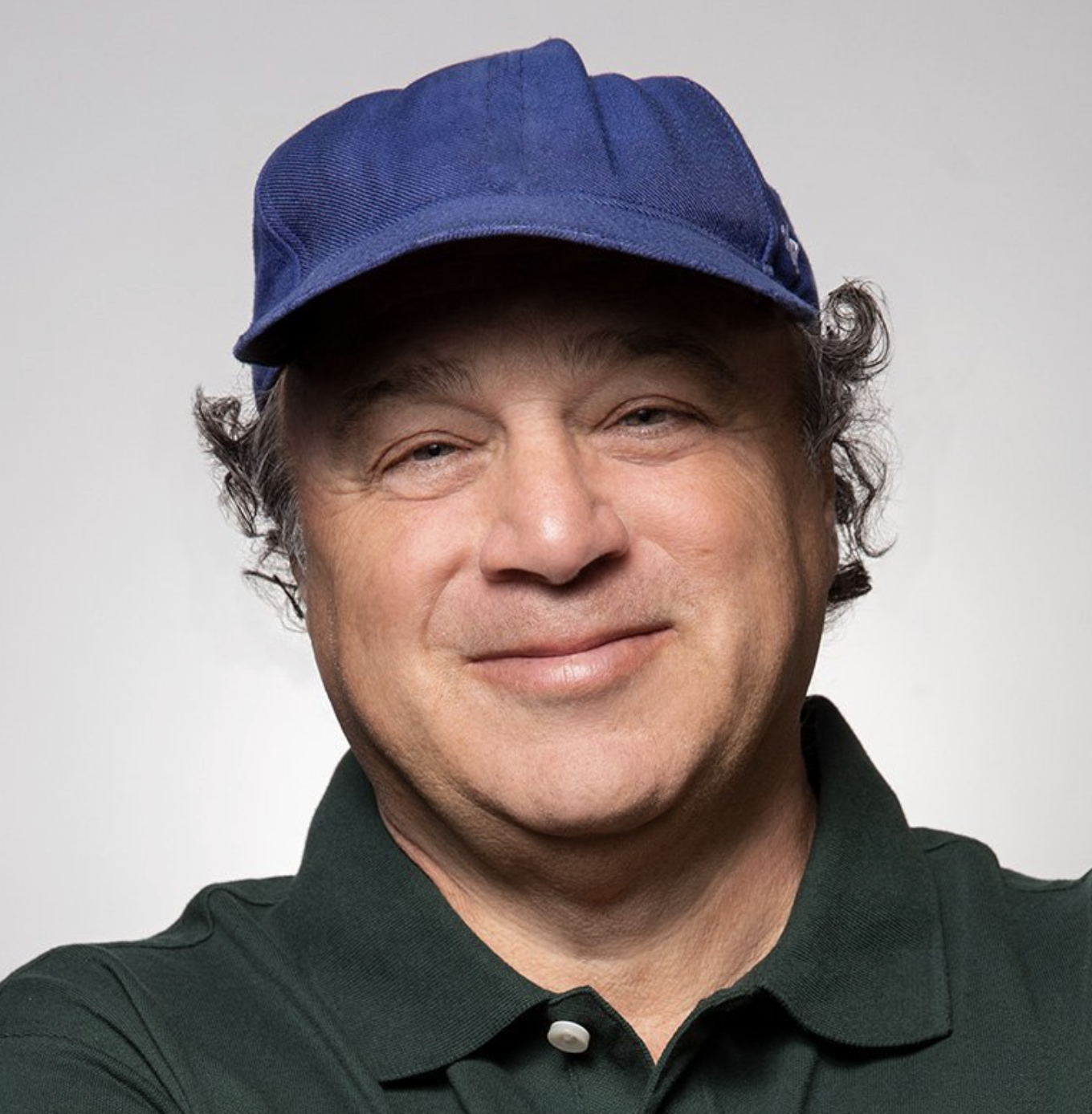 David Wild, Contributing Editor, Rolling Stone, wearing a blue cap and a dark green collared shirt, smiling at the camera.