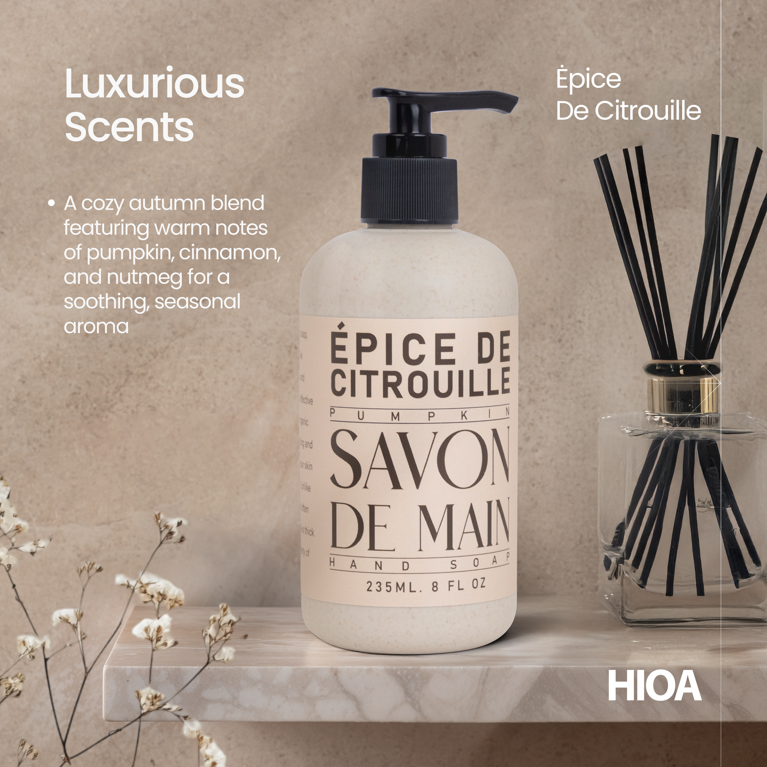 A bottle of pumpkin-scented hand soap labeled in French as 'Épice de Citrouille,' placed on a shelf next to a diffuser with black reeds, with decorative dried flowers nearby.