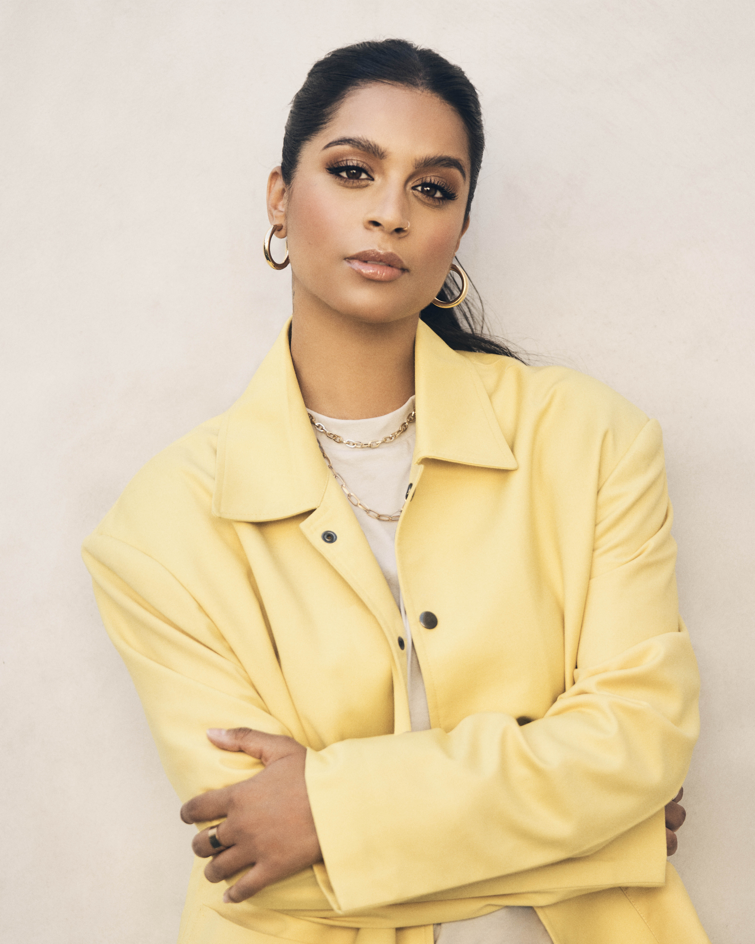 Lilly Singh wearing a yellow jacket and gold earrings