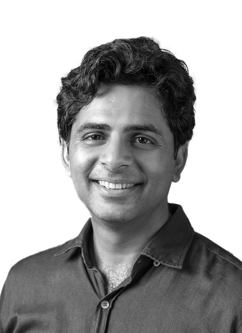 Black and white portrait of a smiling man with dark, wavy hair, wearing a collared shirt