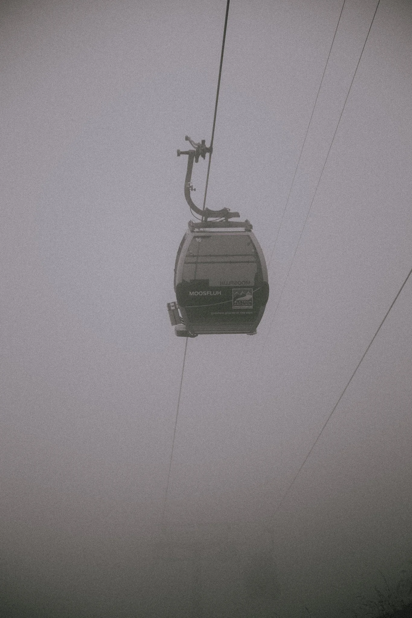 Gondola lift ascending through foggy sky.