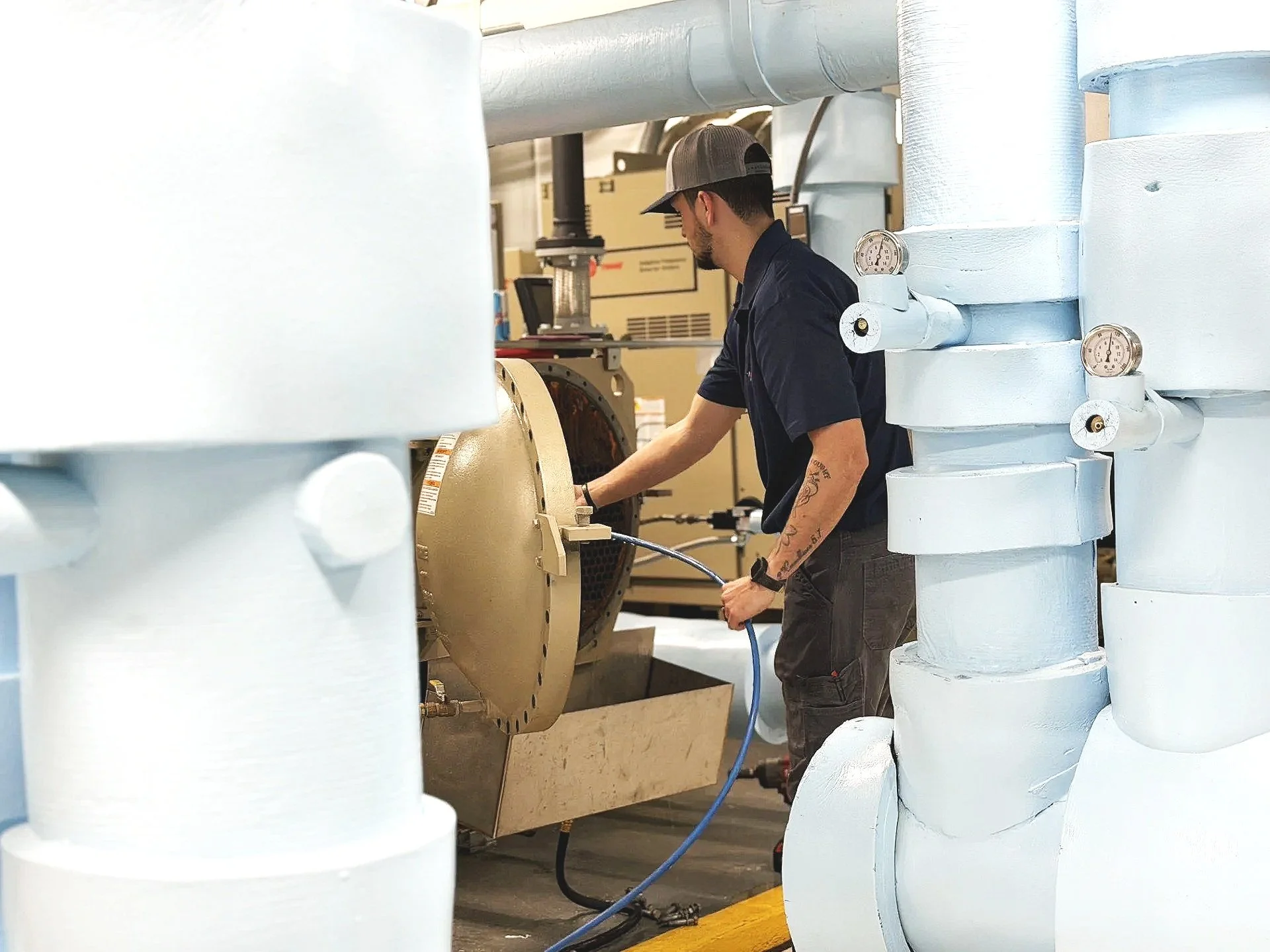 Commercial HVAC technician performing chiller tube cleaning and preventive maintenance inside a mechanical room in Georgia.