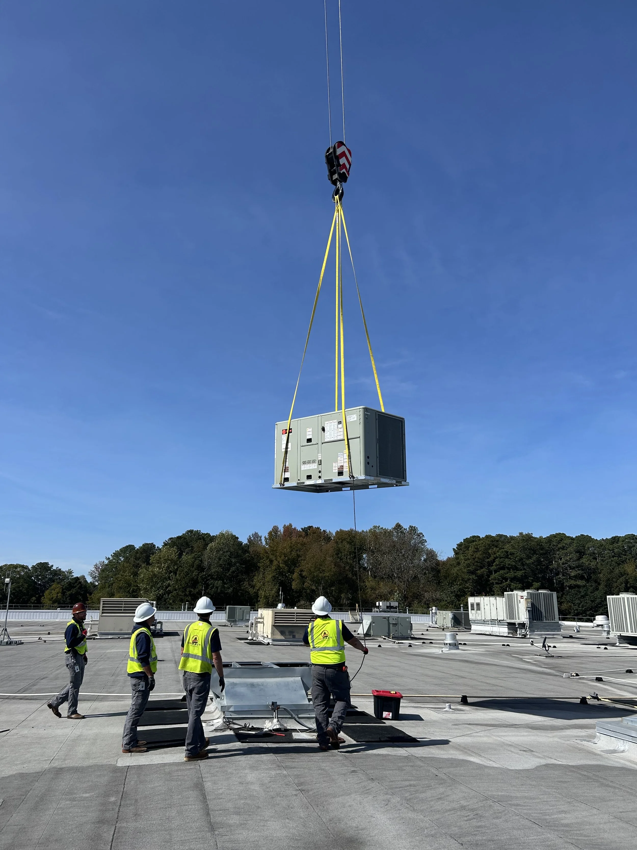 Commercial HVAC rooftop unit installation using a crane by IMPACT Service Group technicians on a commercial building in Georgia.