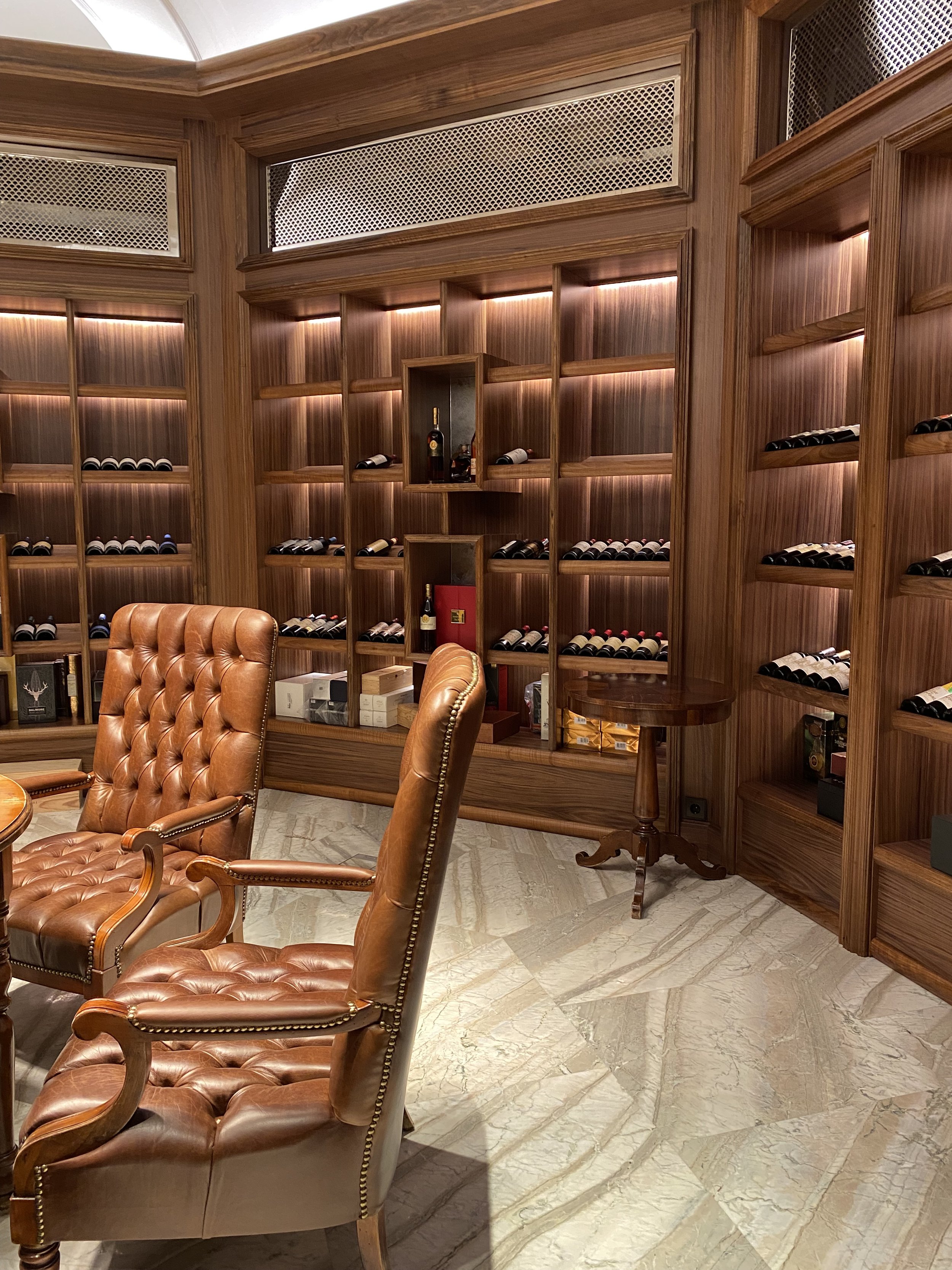 Salle de dégustation de vins avec fauteuils en cuir et étagères remplies de bouteilles de vin.