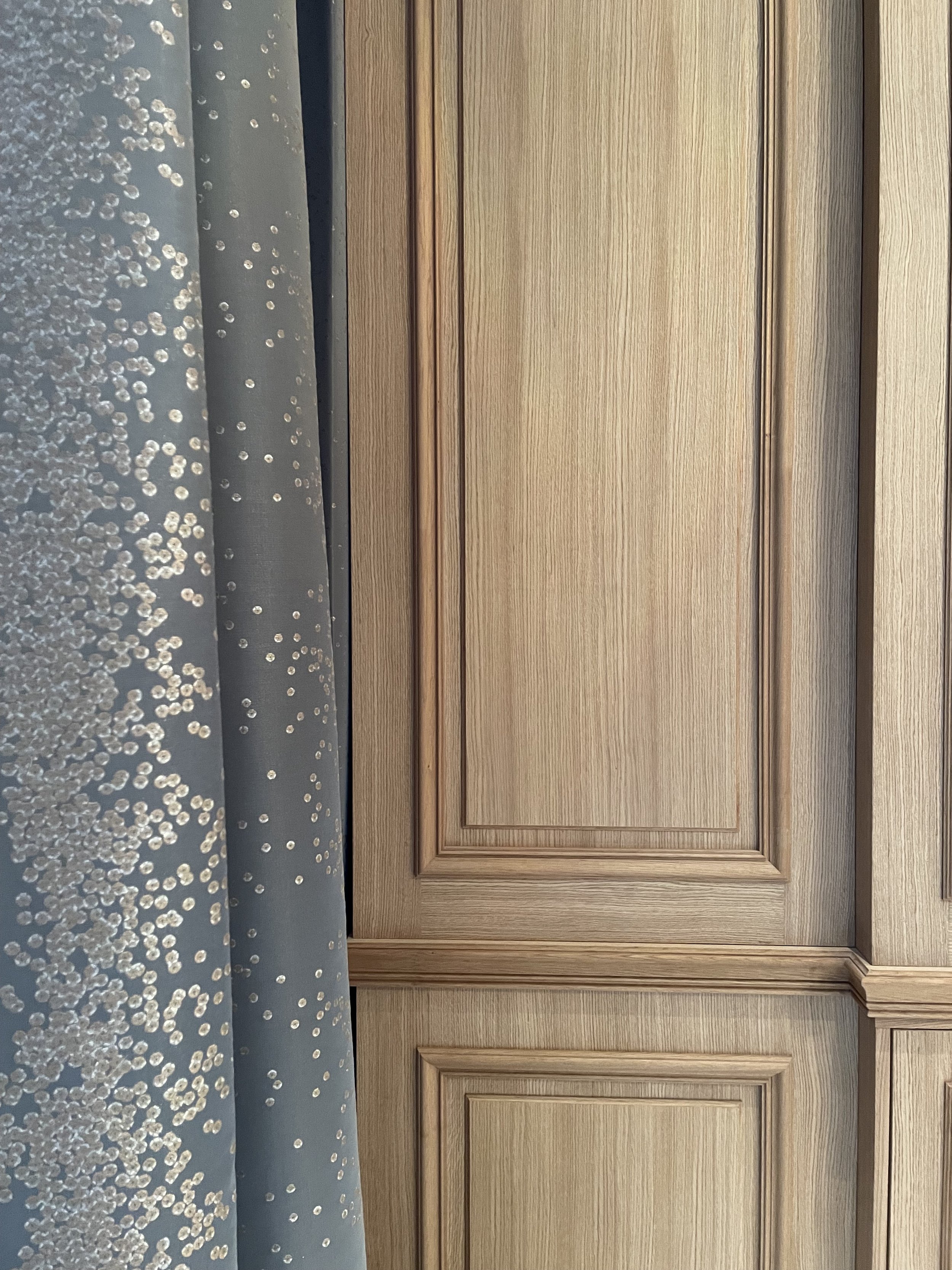 Rideau bleu à motifs et panneau en bois sur un mur.