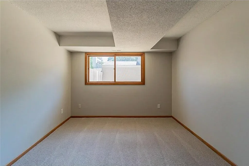 Empty room with a window and beige carpeting.