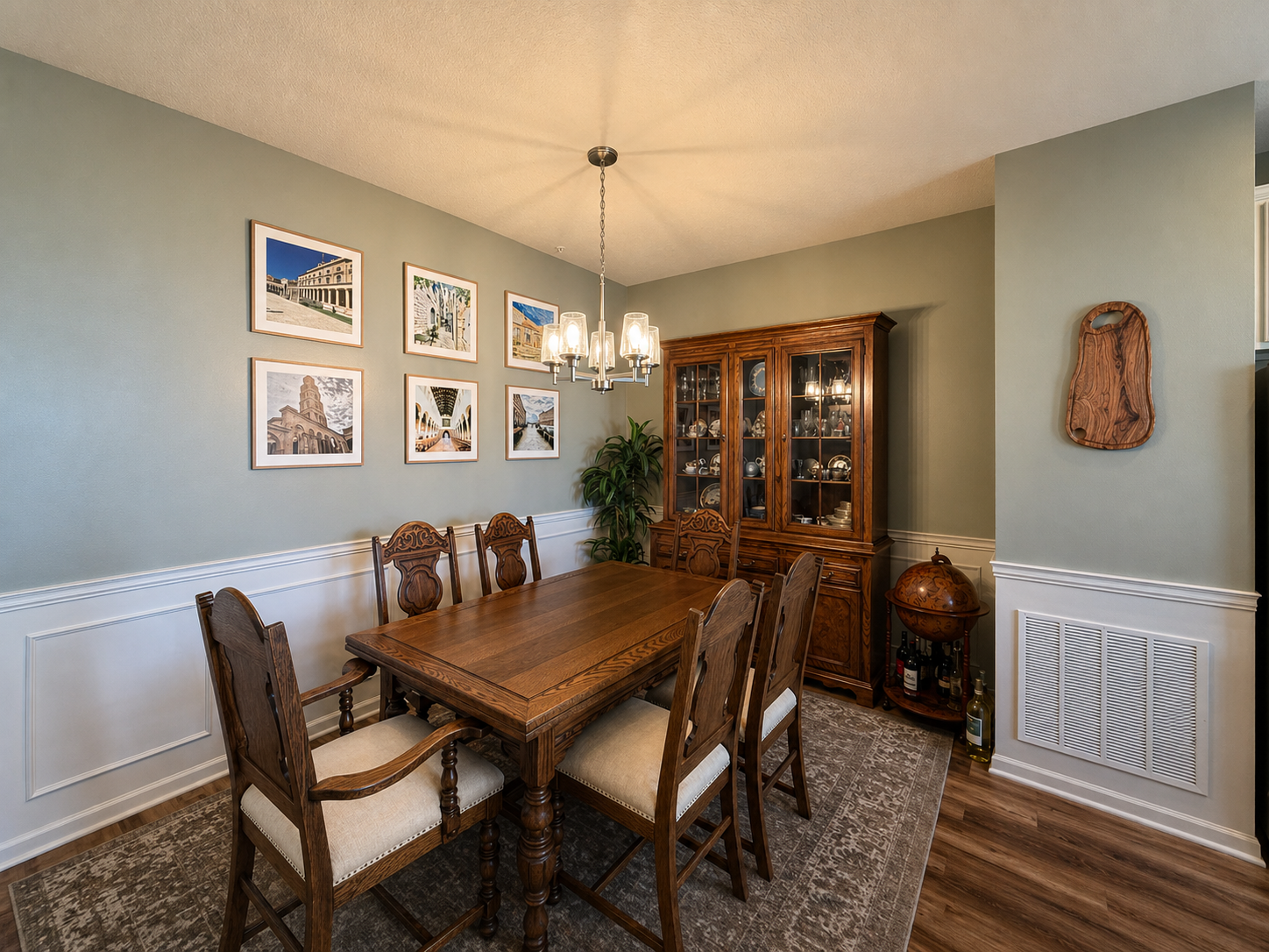 A dining room with a wooden table, six matching chairs, a wooden china cabinet, and framed art on the wall.