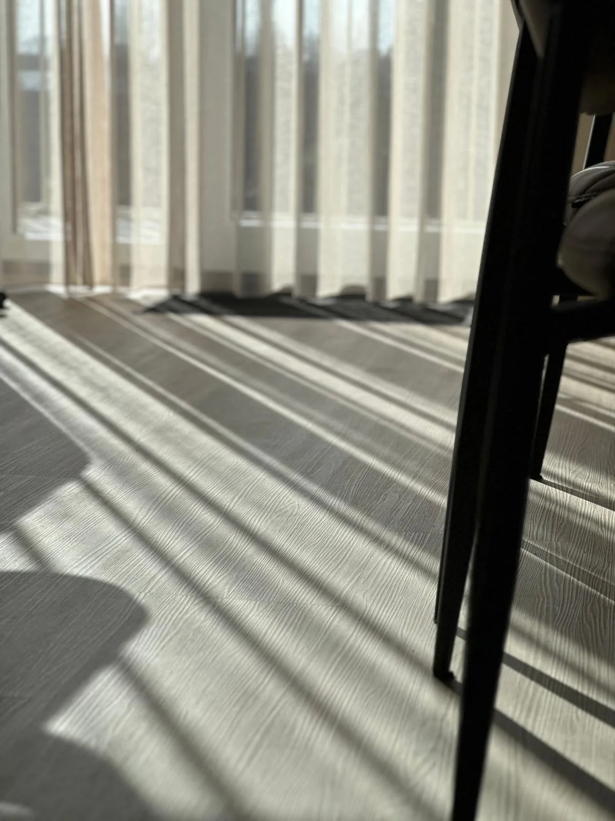 Licht en schaduw patronen op de vloer door raam en gordijnen.