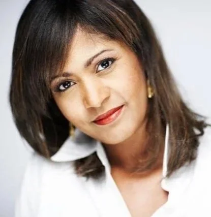 A woman with shoulder-length brown hair, wearing a white shirt, looking at the camera with a slight smile.
