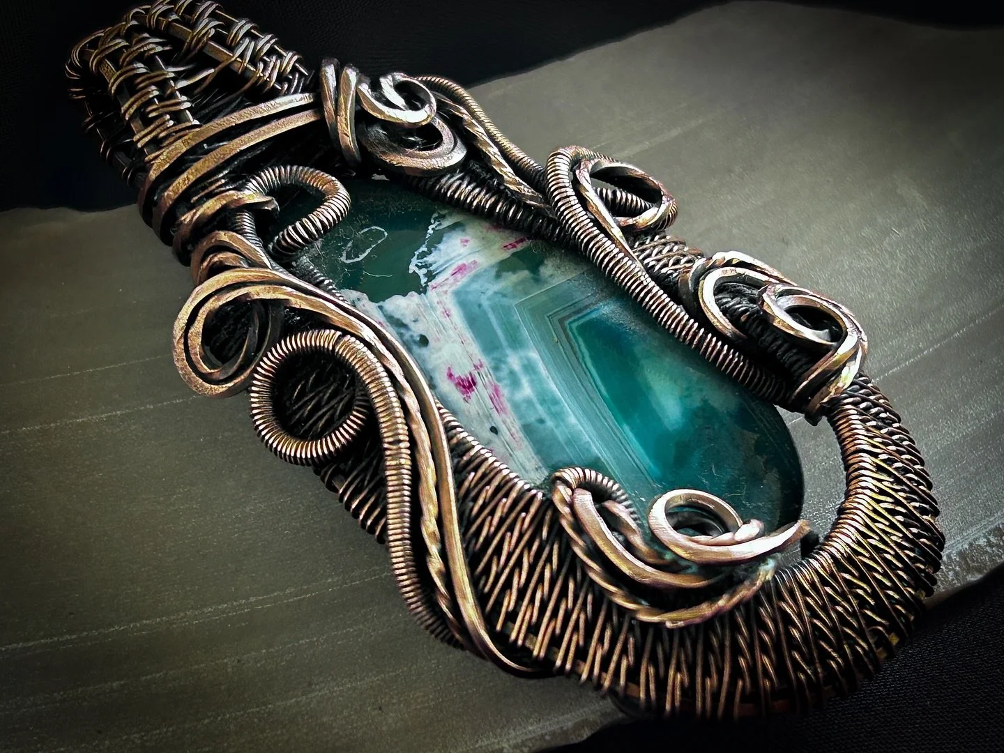 The Elaine&mdash; inspired from the ACOTAR series, this pendant embodies the delicate balance between beauty and resilience. The centerpiece &mdash; a Brazilian agate cabochon rippled in hues of teal, magenta, and soft white &mdash; mirrors the tende