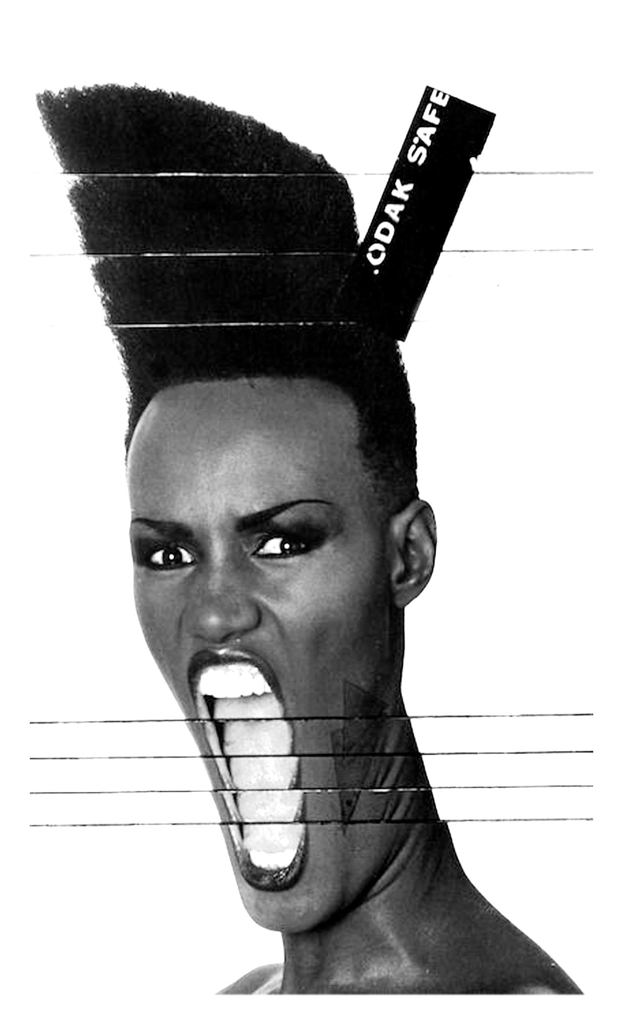 Black and white photo of a woman with an elaborate hairstyle holding a sign that says 'CORK SAFE' behind her head, with an expressive facial expression and tongue sticking out.