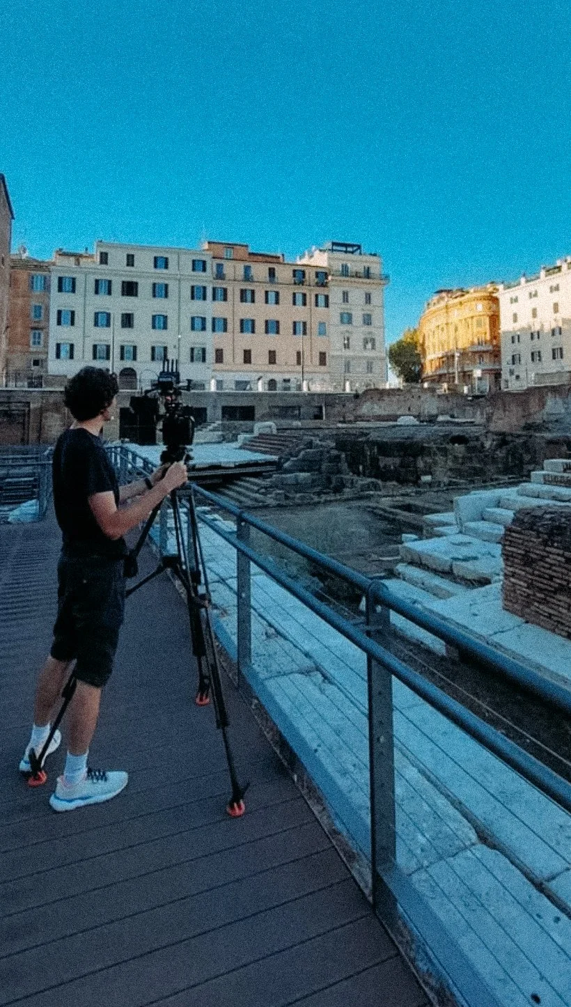 person filming ancient ruins with camera on tripod