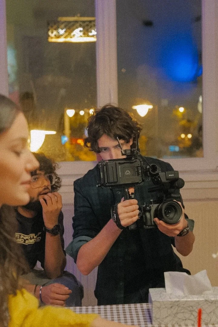 Person holding a camera filming indoors with others around.