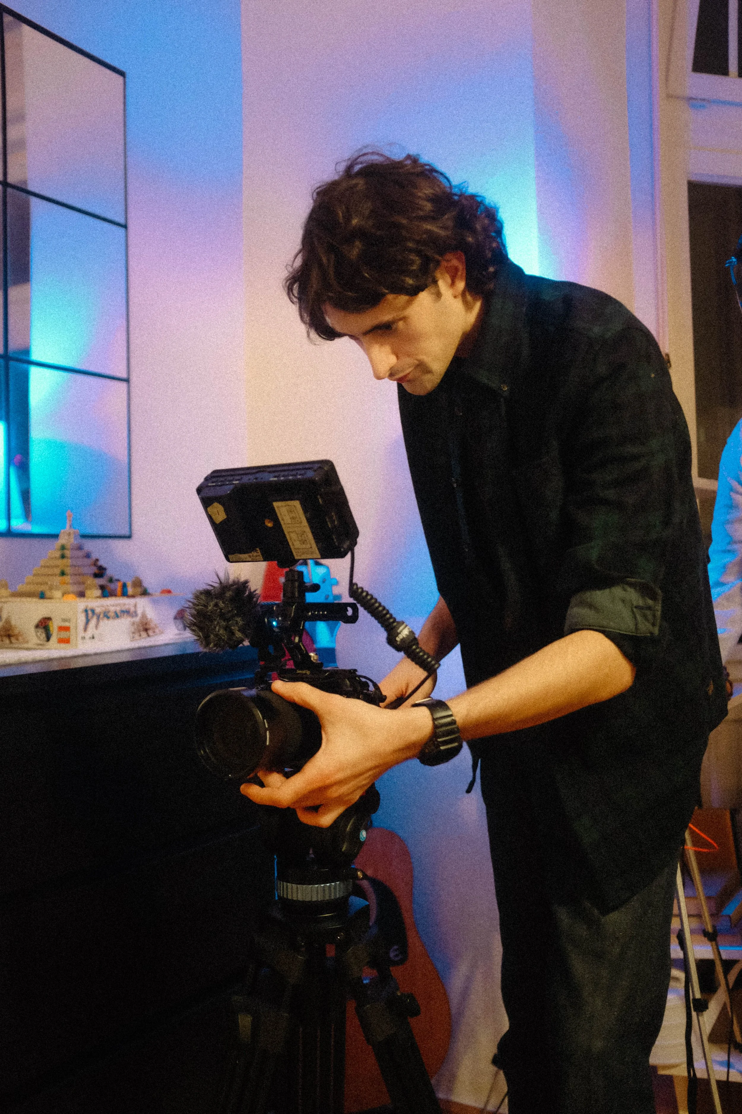 Person adjusting a professional camera on a tripod indoors.
