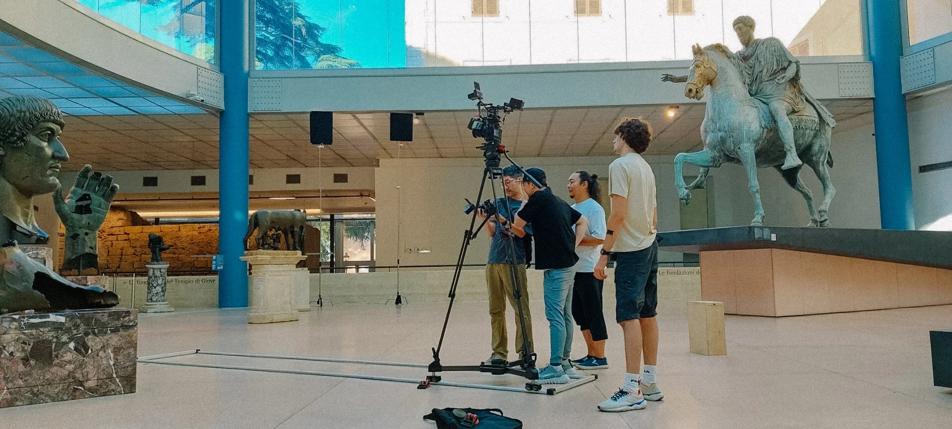 Filmmakers with camera and ancient statue in museum