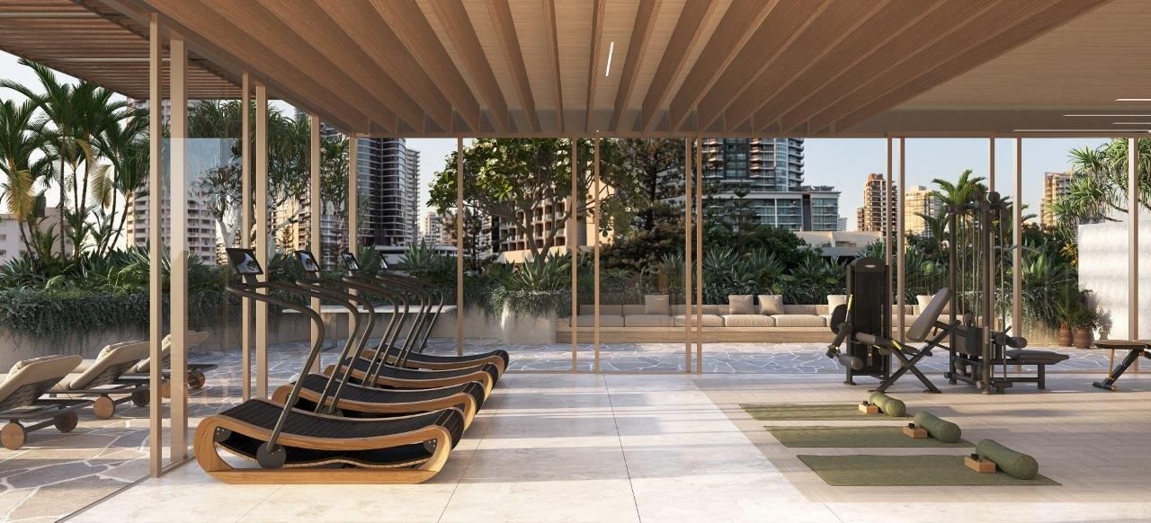 Modern gym with treadmills, exercise equipment, and yoga mats, surrounded by glass walls and outdoor greenery, with city buildings in the background.