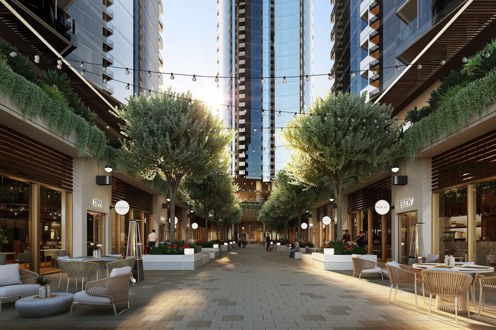 Modern outdoor shopping area with seating, lined with trees and stores, under string lights between tall buildings.