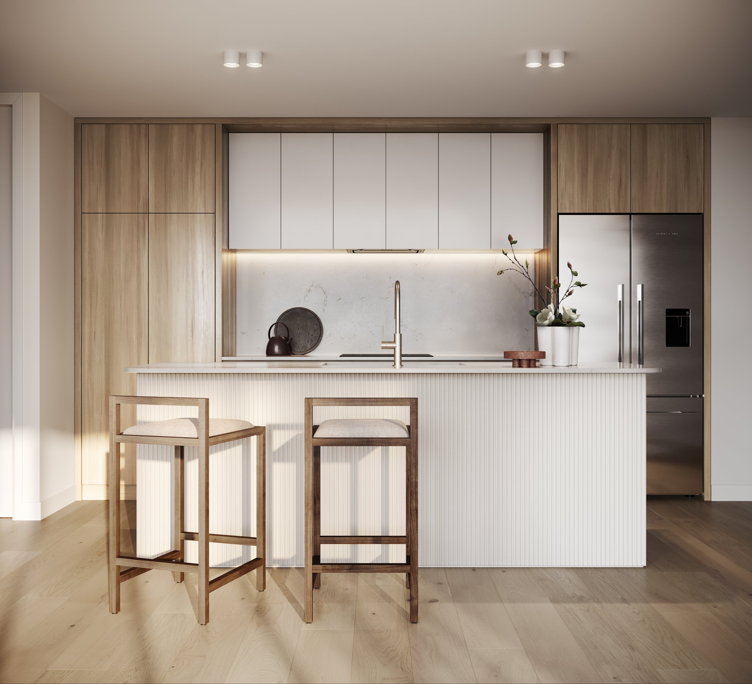 Modern kitchen with a wooden island and two bar stools. Features light wood cabinetry, a stainless steel refrigerator, and minimalist decor including a vase with flowers. The kitchen has a sleek design with ample lighting and neutral colors.