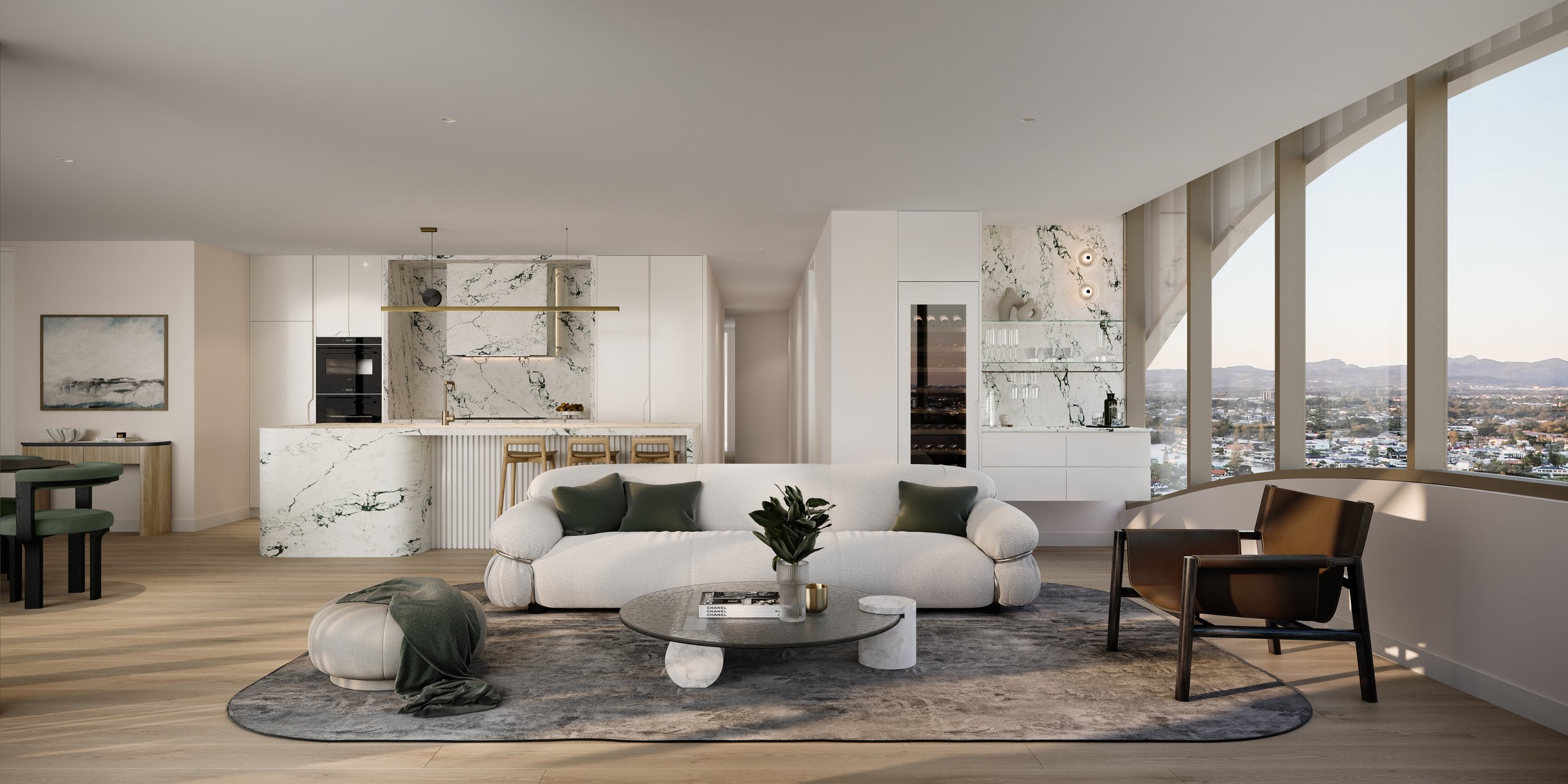 Modern living area with a white plush sofa, green cushions, a glass coffee table, and marble accents. A kitchen with a marble island and stools is in the background. Large windows offer a city view.