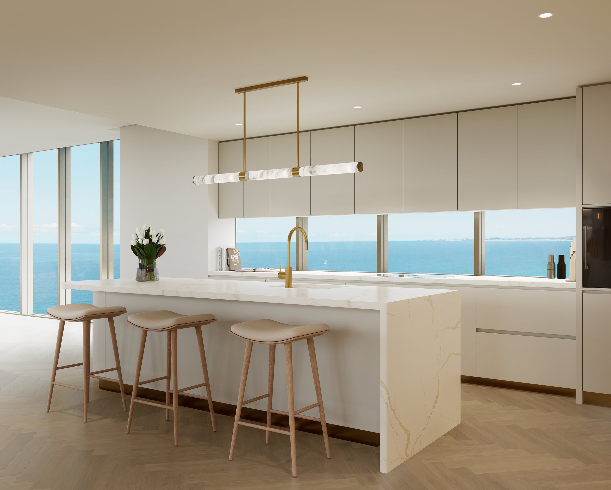 Modern kitchen with ocean view, featuring white cabinetry, a marble island with bar stools, gold fixtures, and large windows overlooking the sea.
