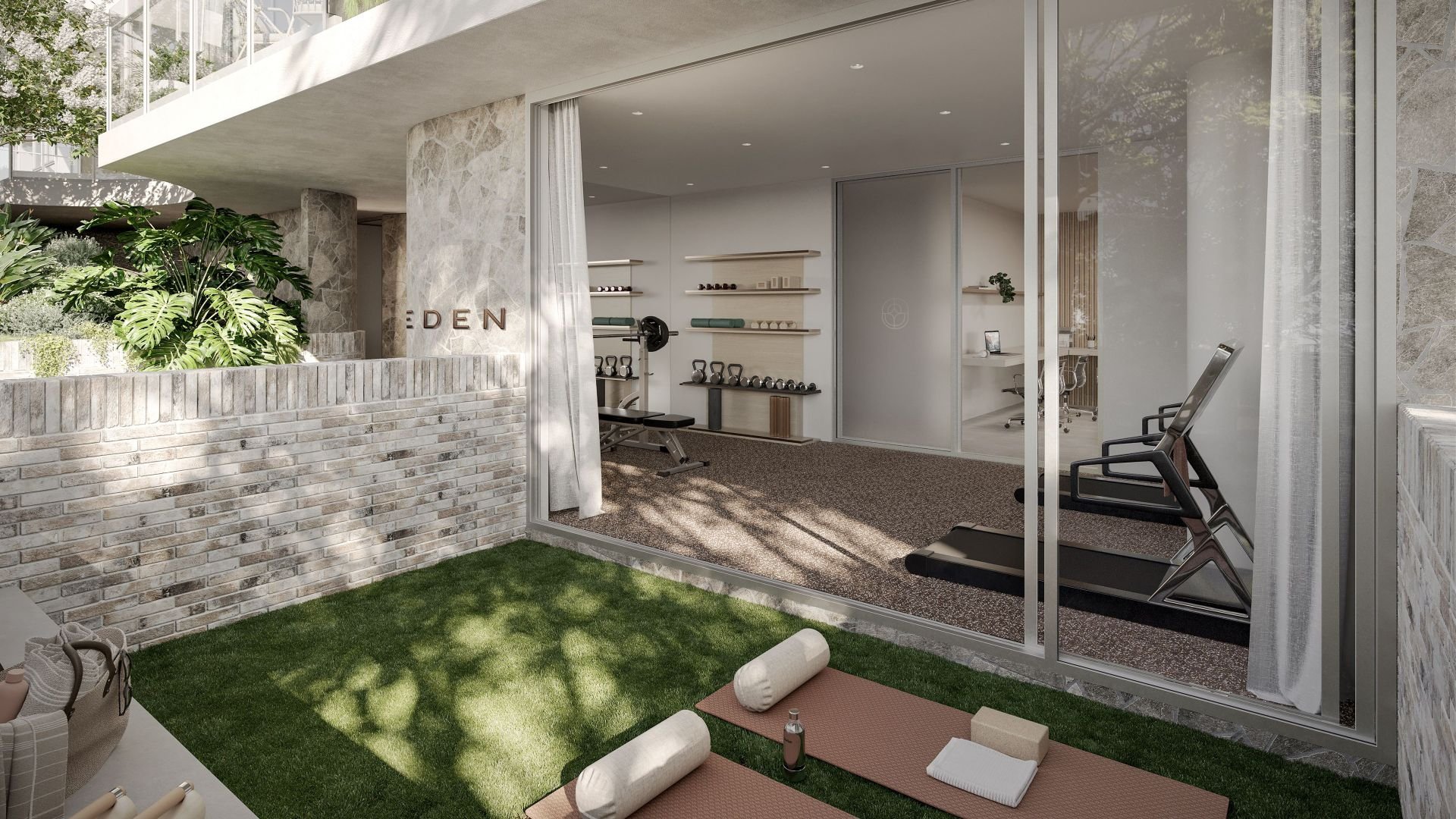Modern outdoor gym area with yoga mats and exercise equipment, surrounded by greenery and glass walls.