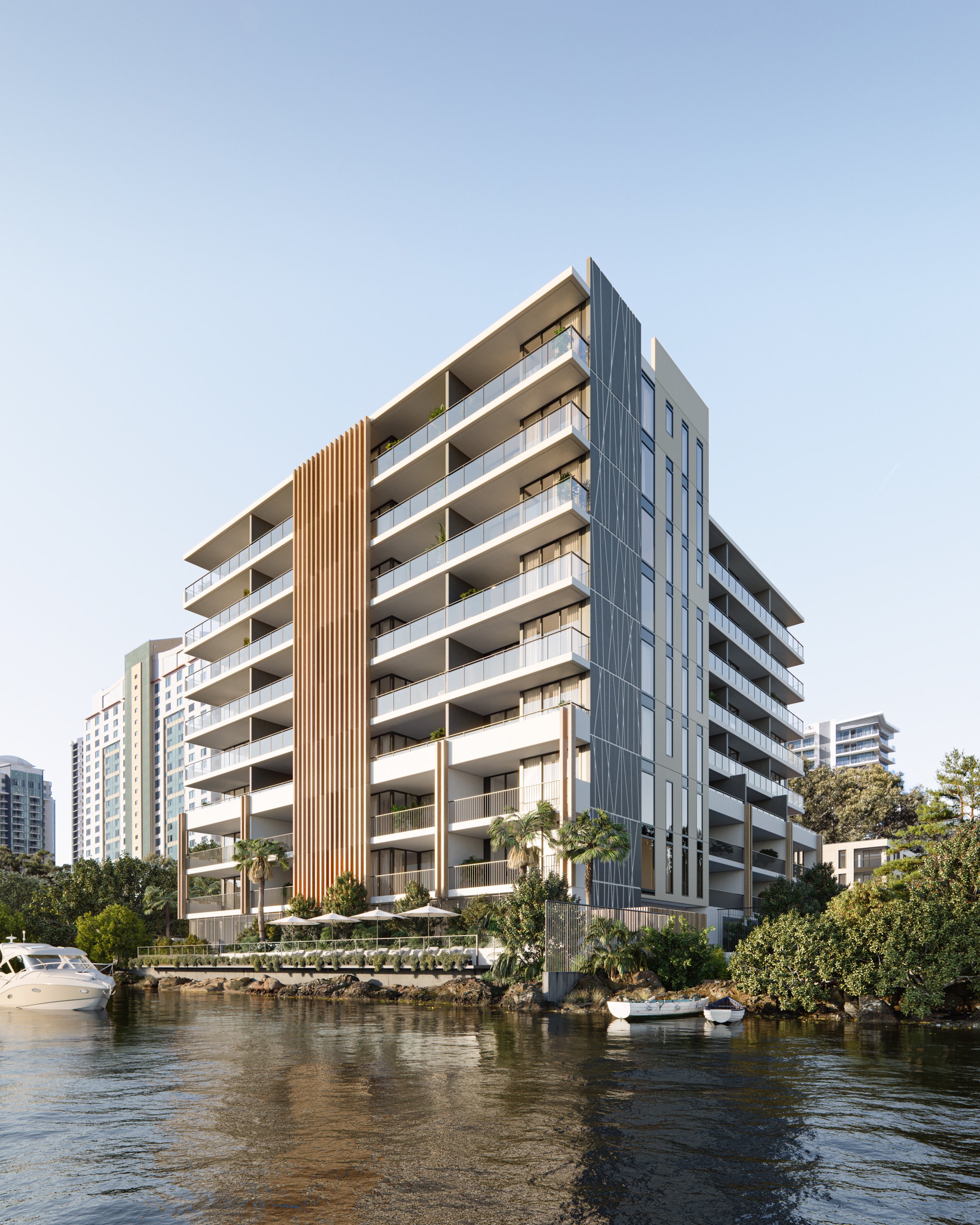 Modern waterfront apartment building with balconies, surrounded by trees, near a river with boats.