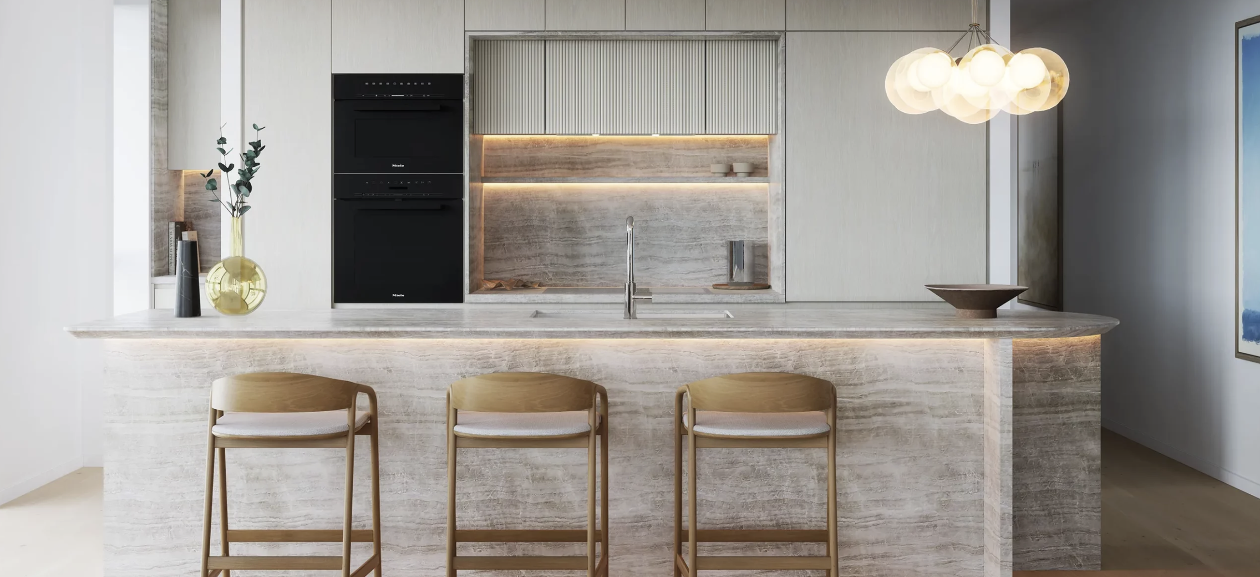 Modern kitchen design with marble island, bar stools, built-in ovens, pendant lighting, and decorative vases.