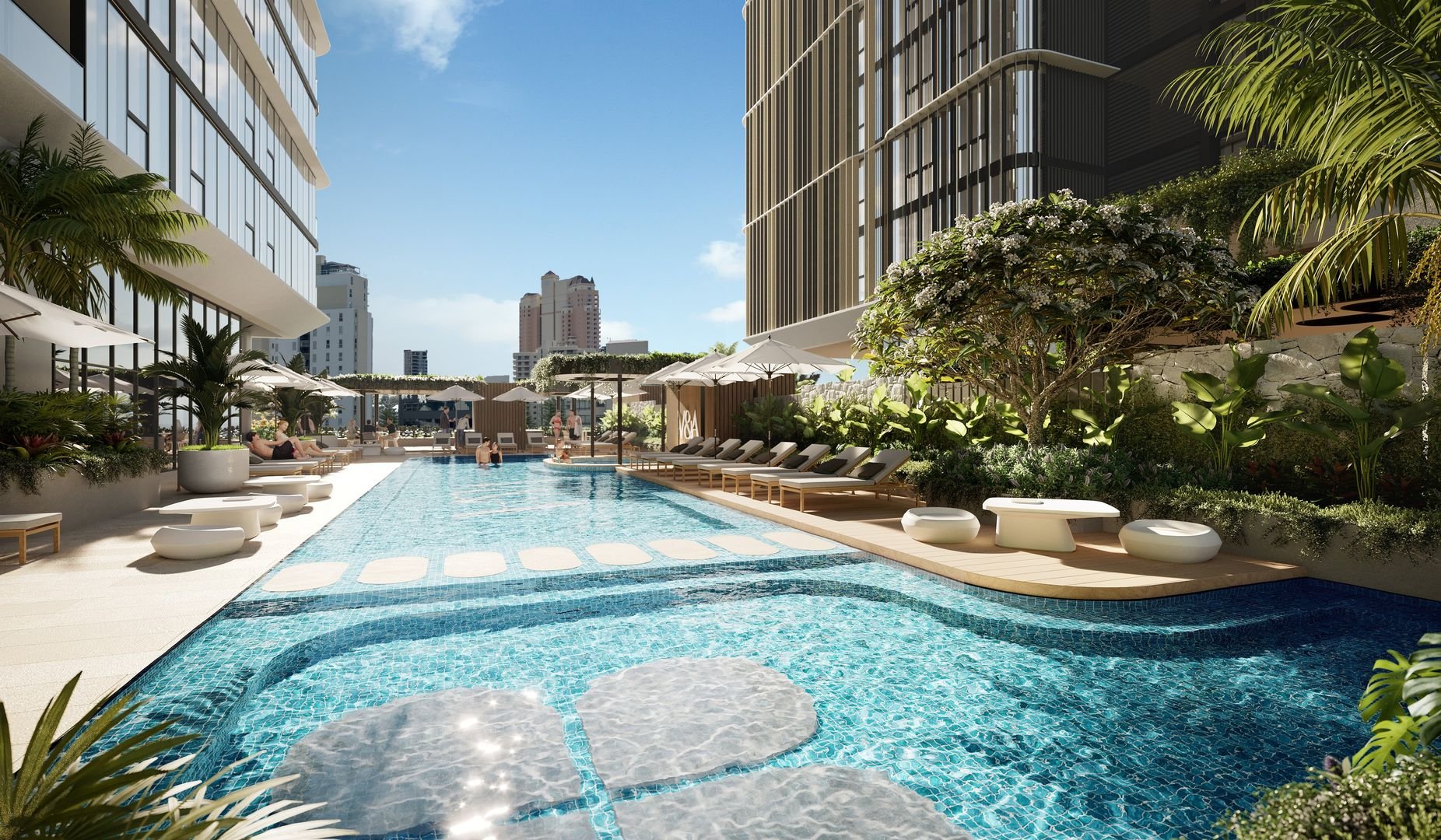 Modern outdoor pool area with sun loungers, umbrellas, and lush greenery, surrounded by tall buildings under a clear sky.