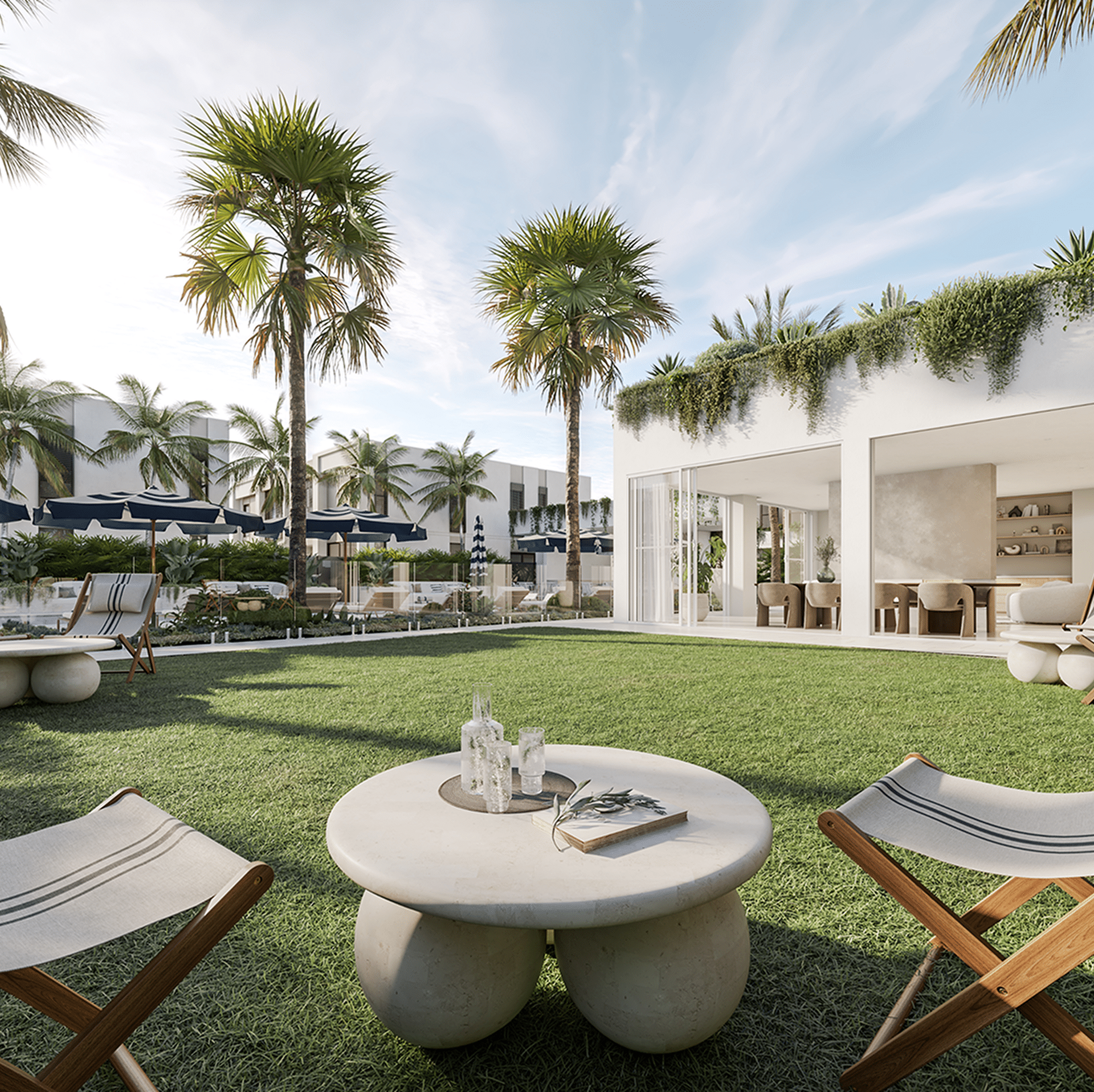 Modern outdoor patio with palm trees, grass lawn, and patio furniture including round tables and folding chairs. Luxurious open-concept living area with large glass doors and lush greenery overhead.