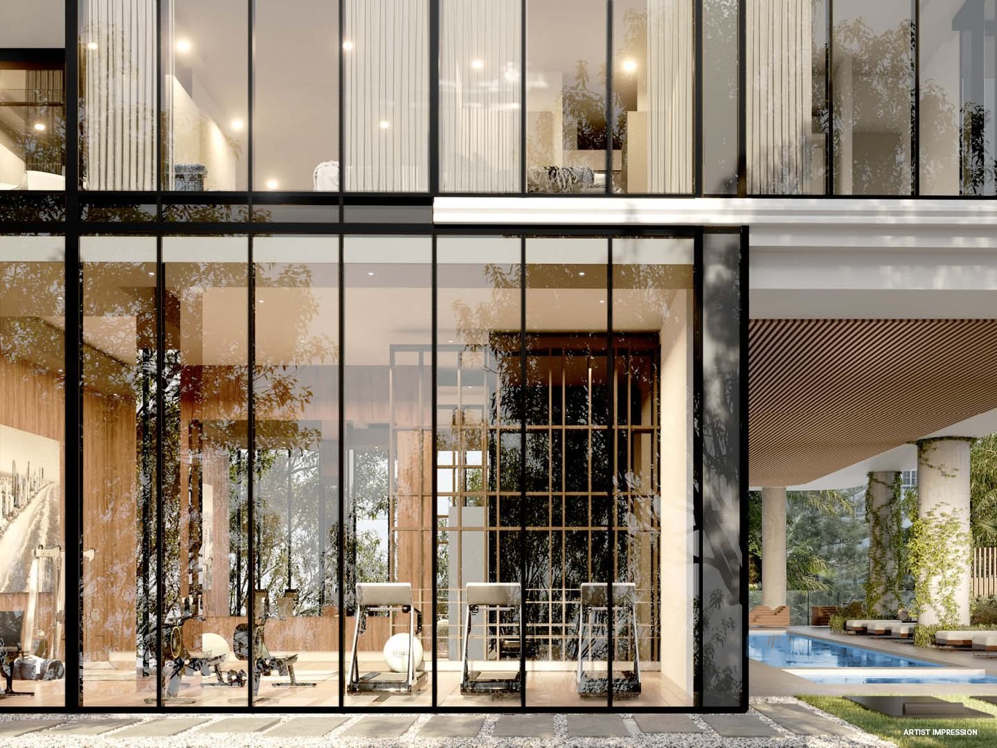 Modern building with large glass windows, revealing an interior with exercise equipment, artwork, and an outdoor pool area nearby.